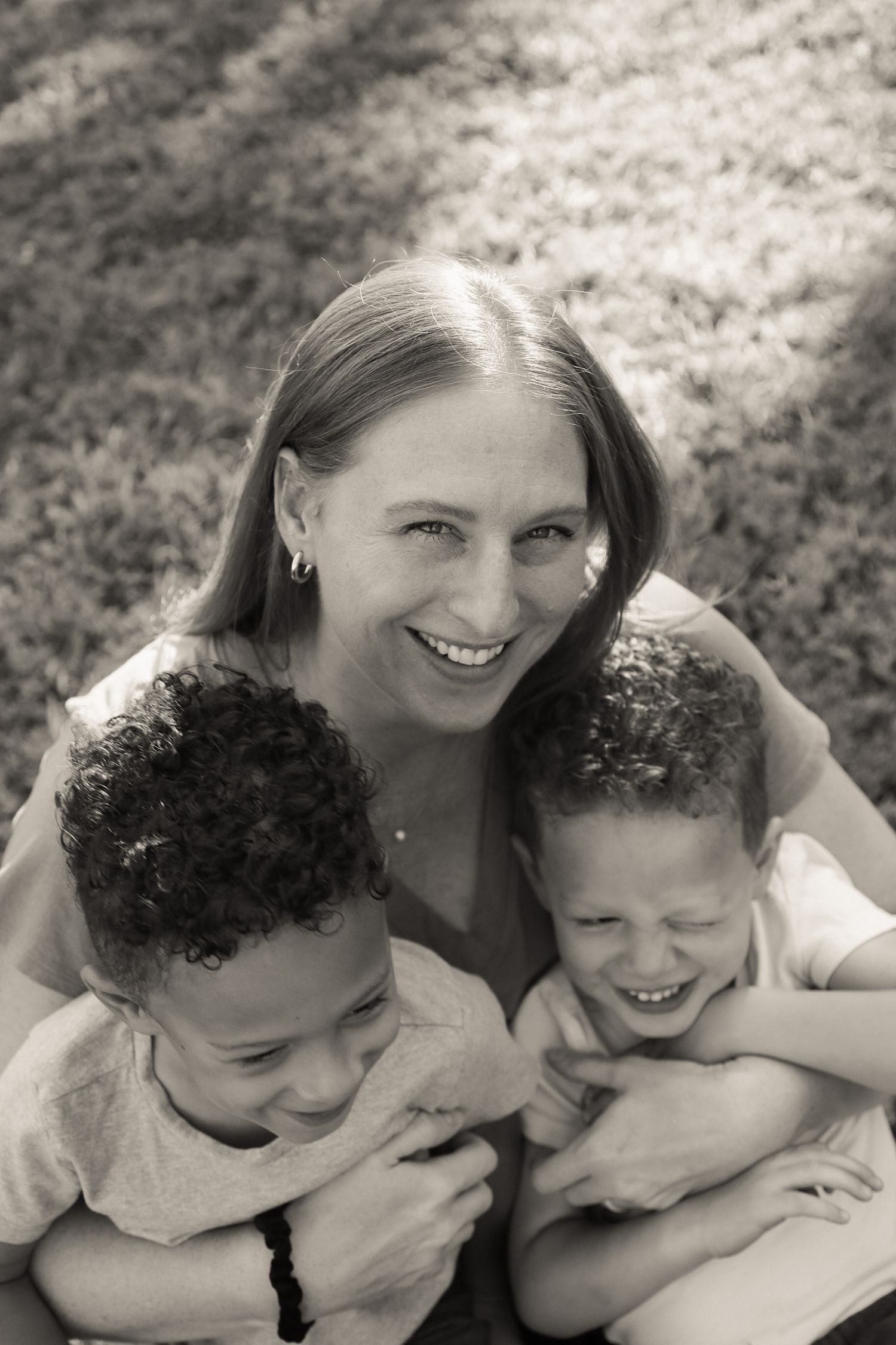 Black and white portrait series showing joyful family embraces outdoors.