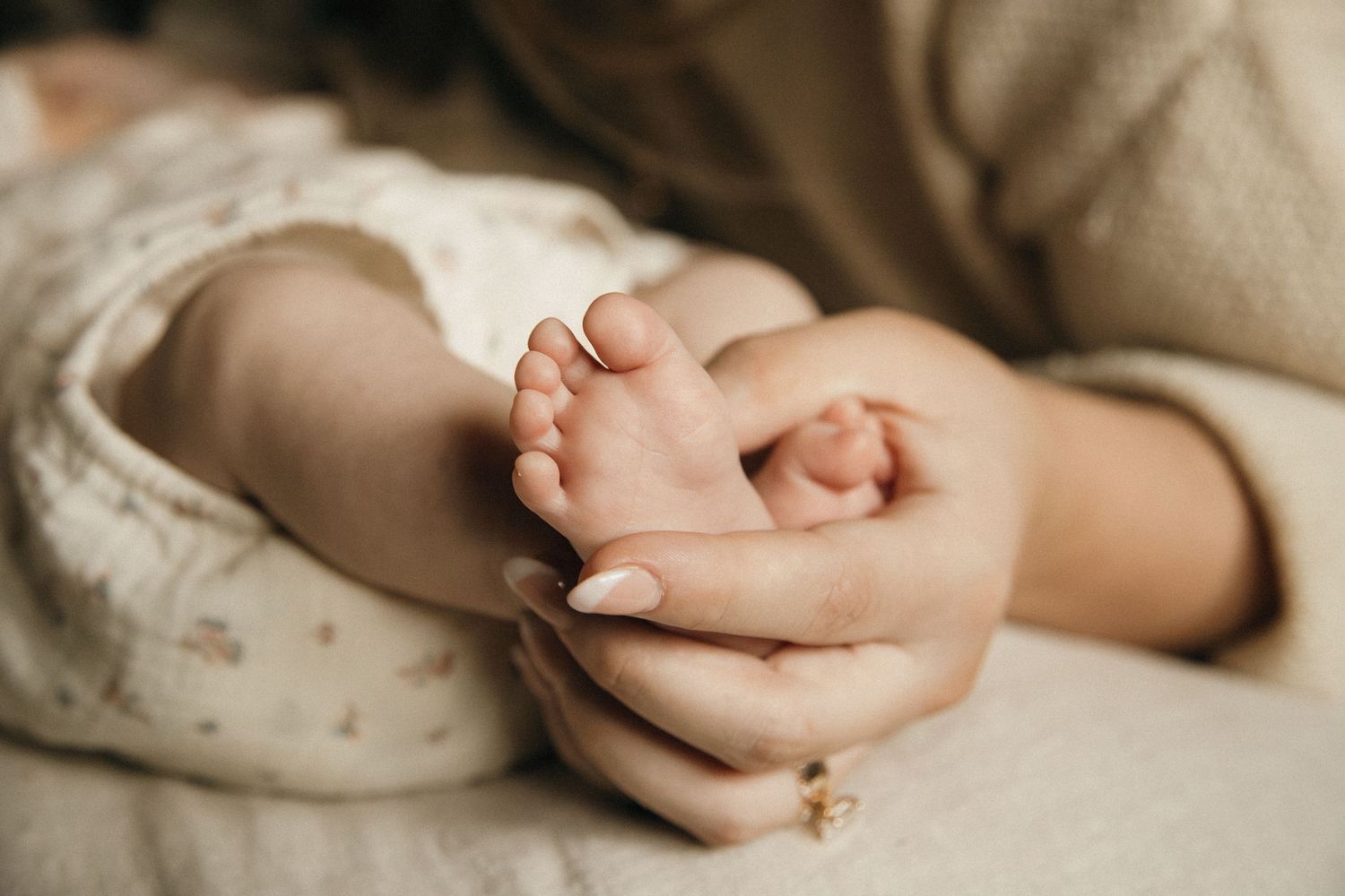 Close-up detail shot of hands resting on neutral fabric in gentle lighting.