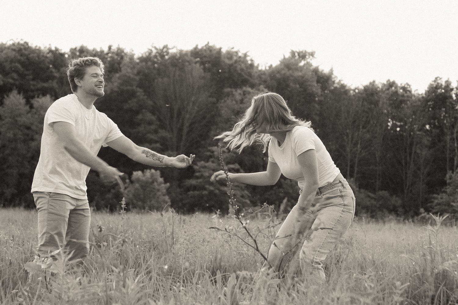 Two people dance and laugh together in a sunlit meadow.