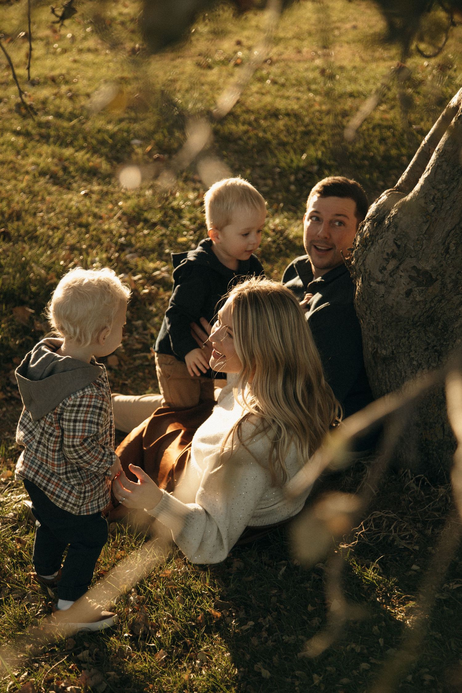 A family enjoys a candid moment together outdoors during golden hour in a natural setting.