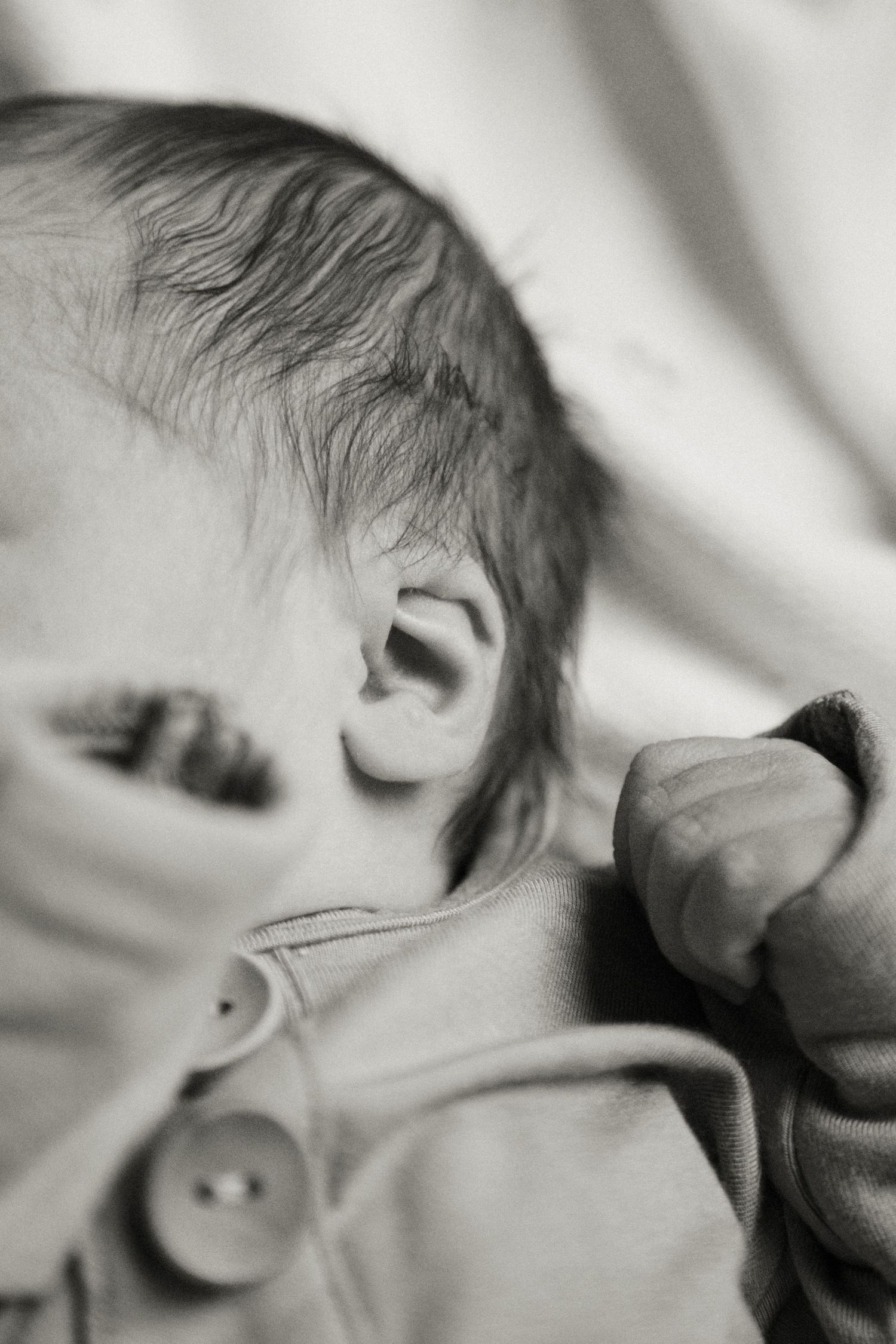 Gentle black and white close-up profile of a sleeping infant.