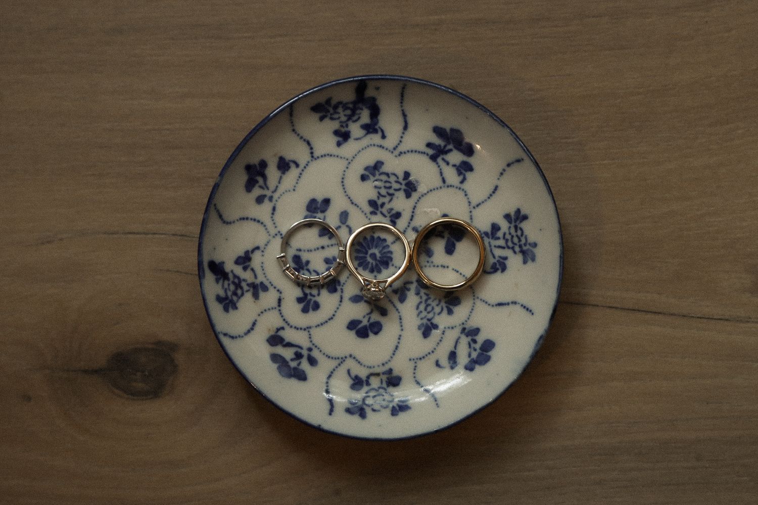 Wedding rings displayed on a decorative blue and white china plate with floral pattern.