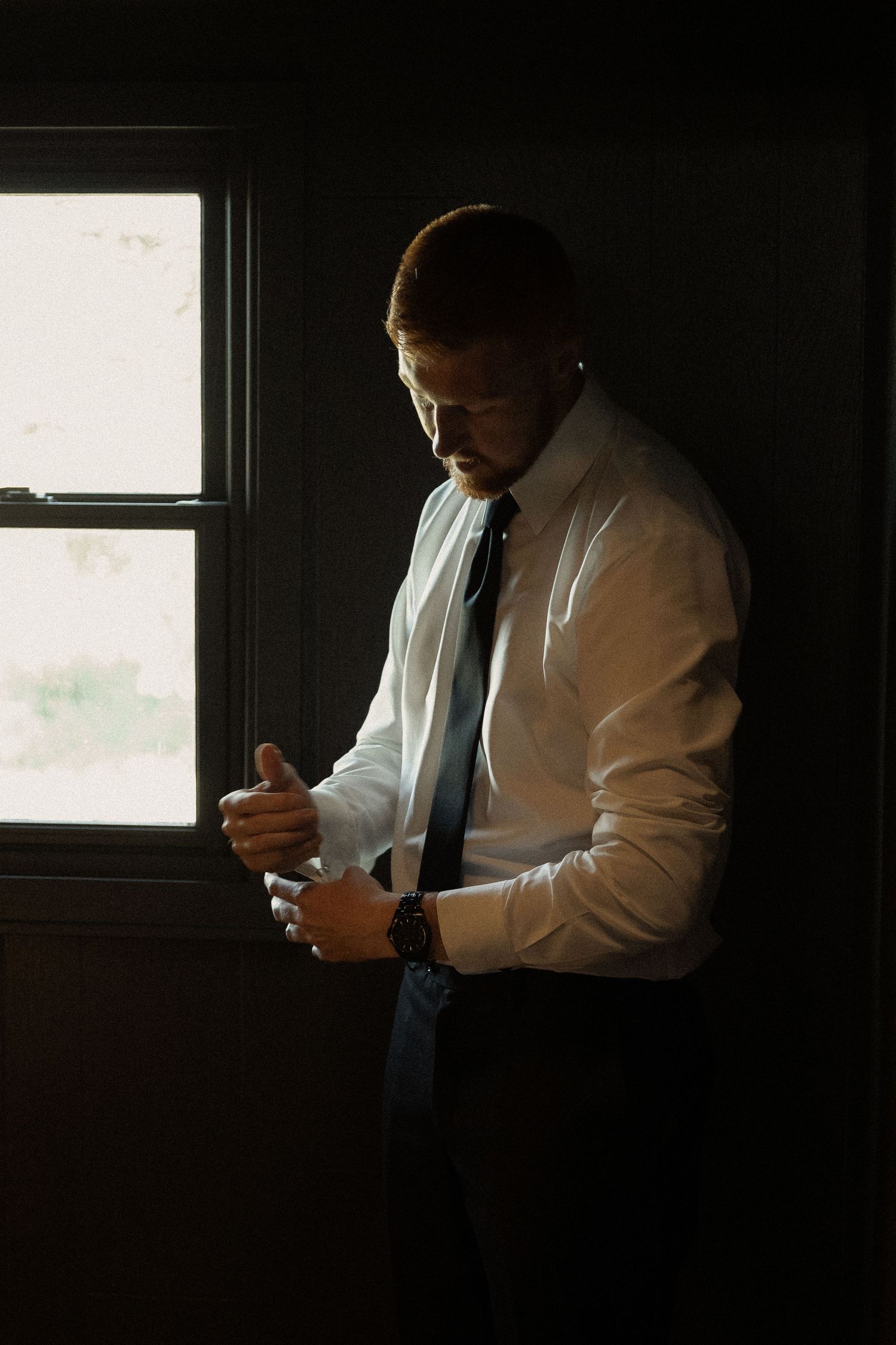 A silhouetted figure stands by a window in dramatic lighting.