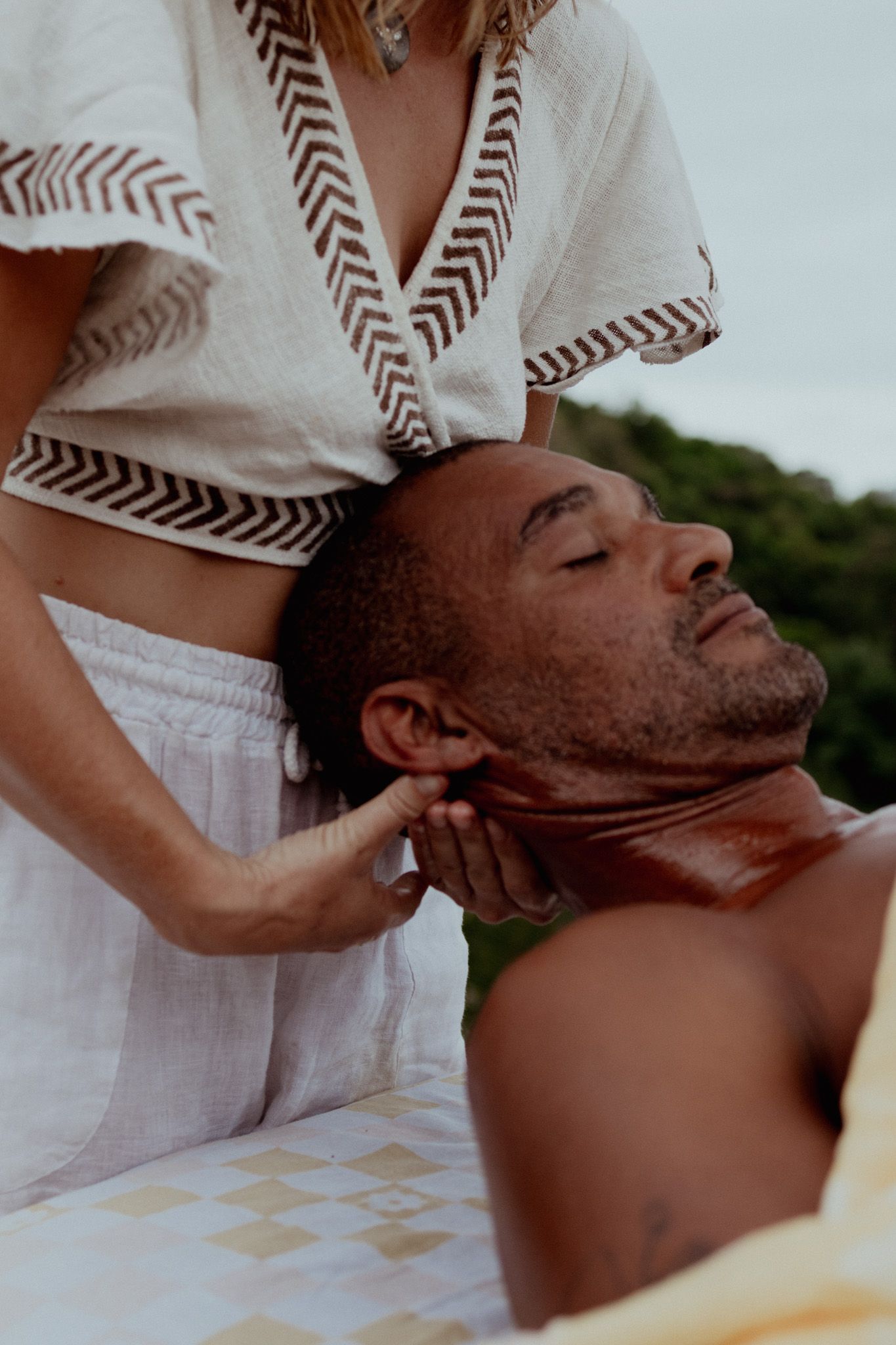 Therapeutic massage session being performed outdoors with natural background.