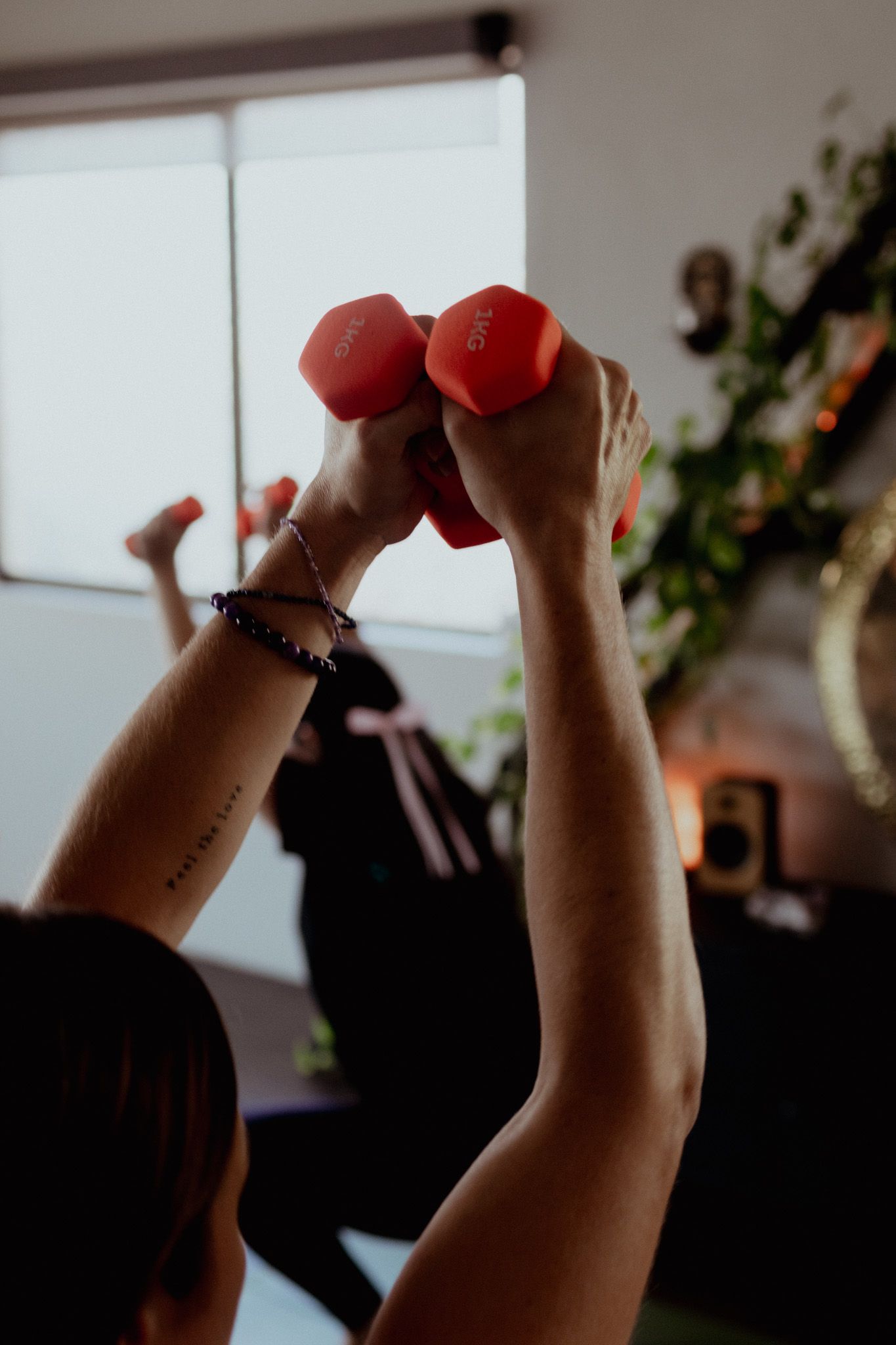 Hands holding small red weights during a group fitness class.