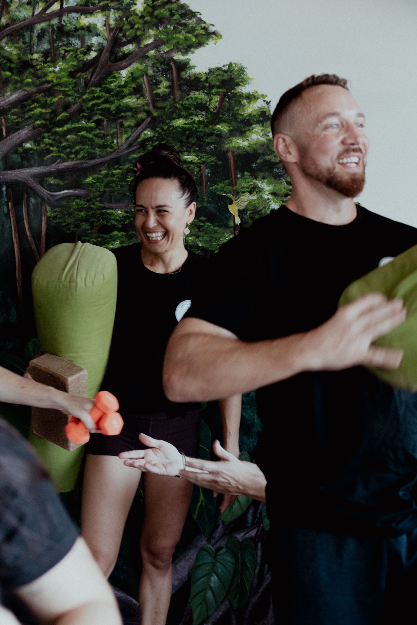People laughing and interacting during a fitness class with small weights.