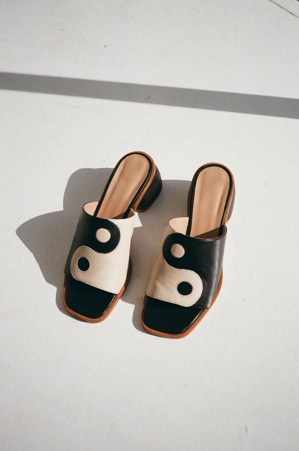 Black and white yin yang leather mule sandals with block heel and tan insole on white surface.