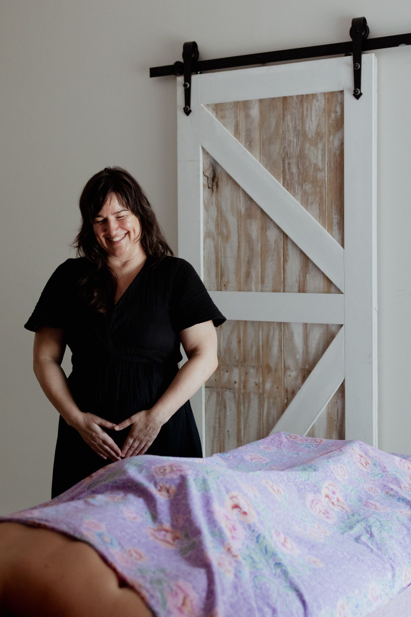 Massage therapist preparing treatment room with floral patterned linens.