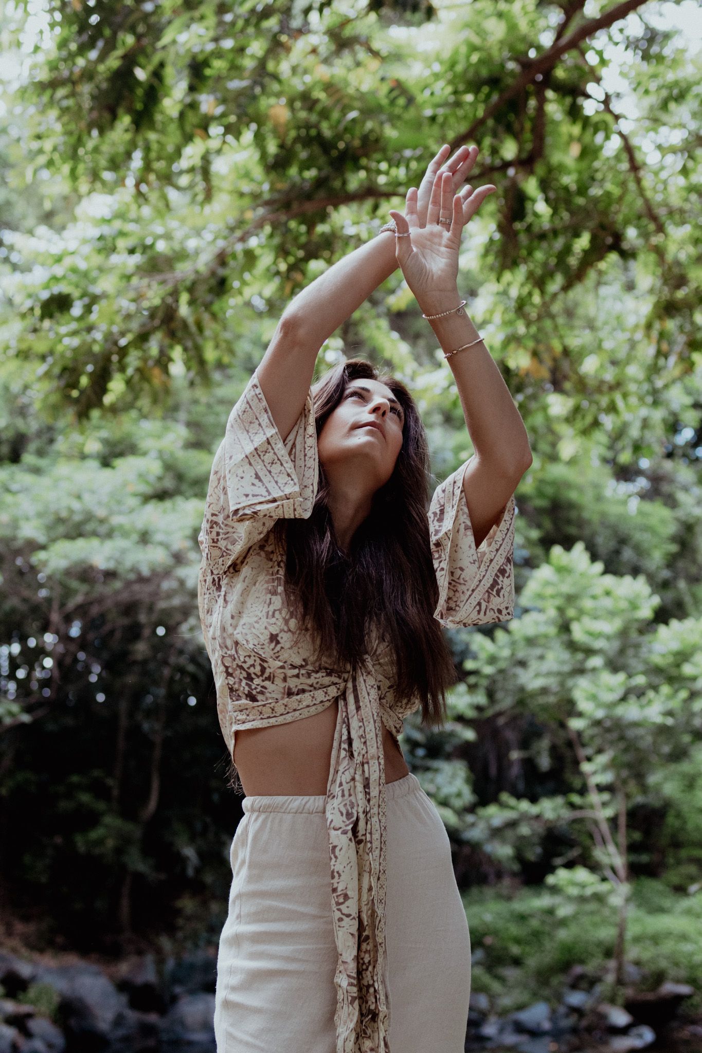 A carefree moment captured in a wooded setting with flowing white dress and lace details.
