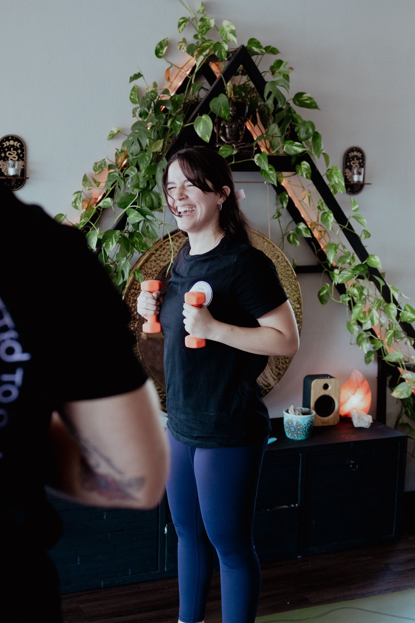 Person exercising with small hand weights in a studio with plants and natural light.