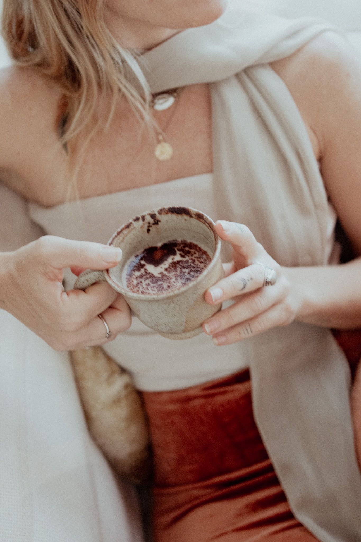 Hands holding a ceramic bowl with dark contents against light clothing.