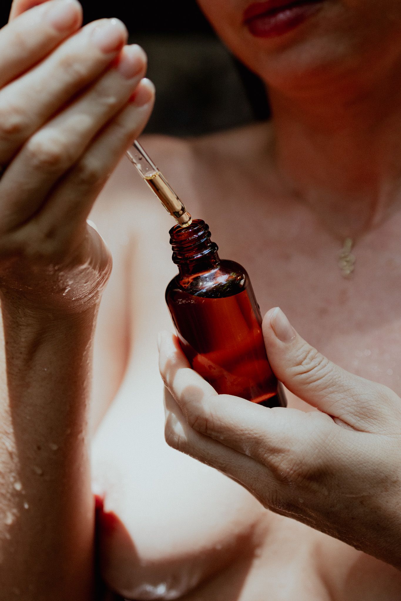Close-up shots of hands holding and using a small amber glass dropper bottle.