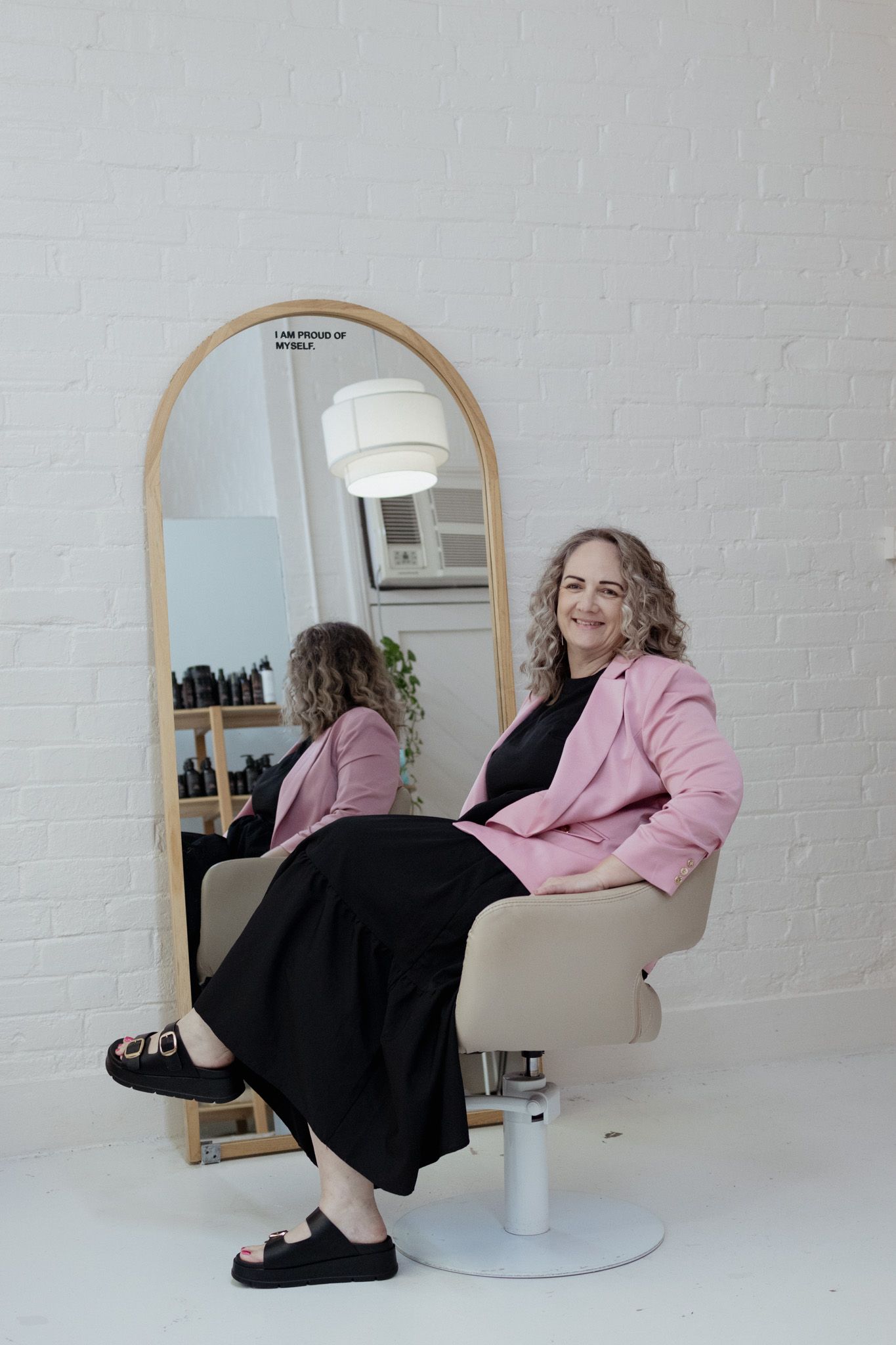 Interior of a modern salon with arched mirrors and minimalist white brick walls.