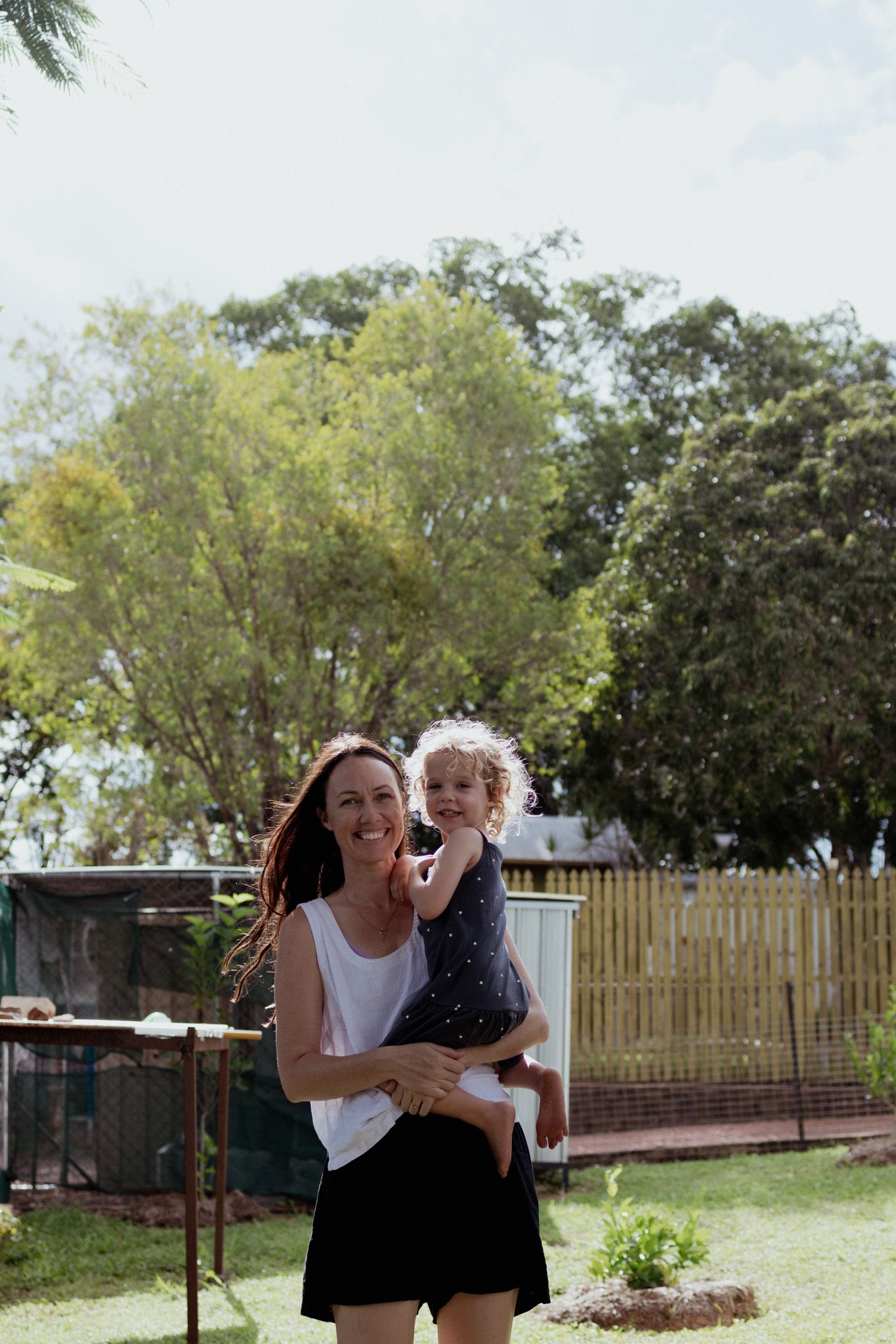 Playful outdoor sequence in a backyard with wooden fence and greenery.