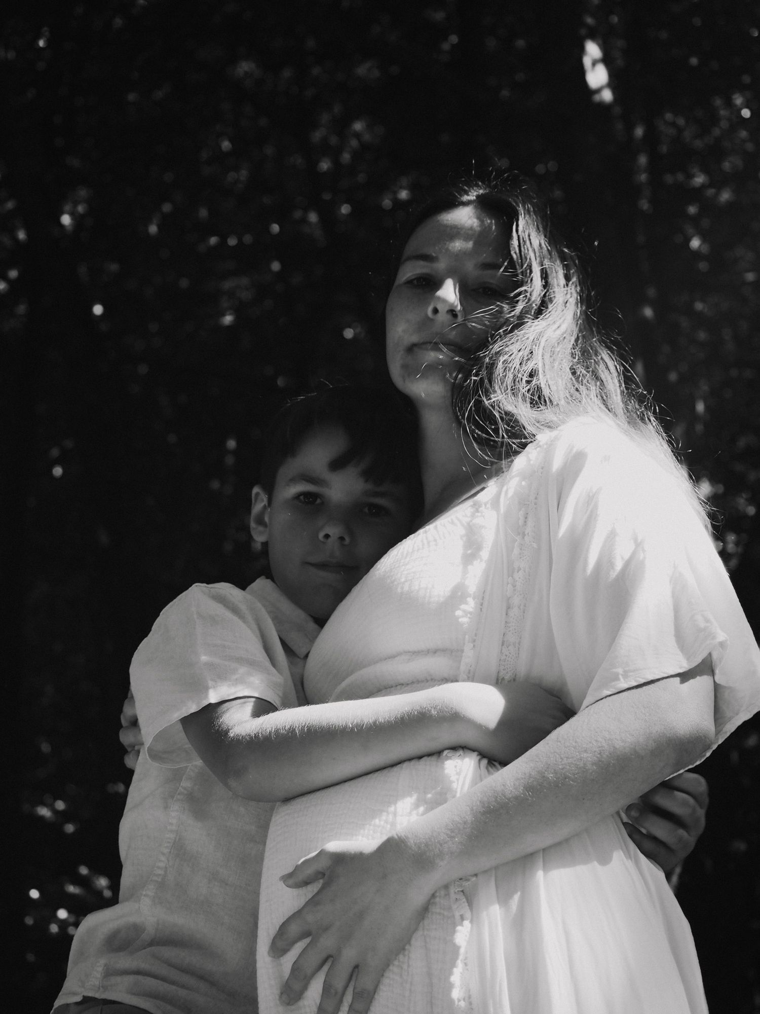 Black and white portrait showing intimate moment between parent and child outdoors.