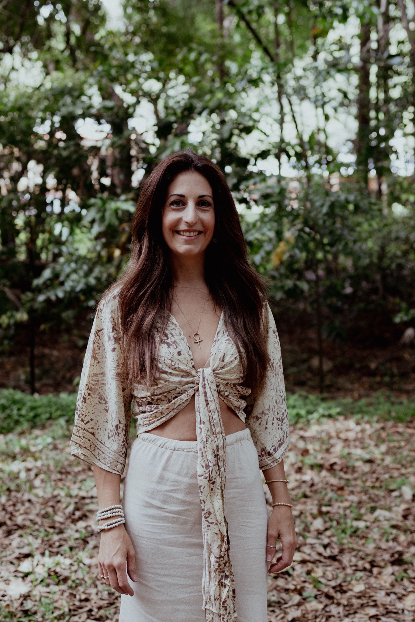 A bohemian photoshoot in a forest setting featuring white lace and floral crown styling.