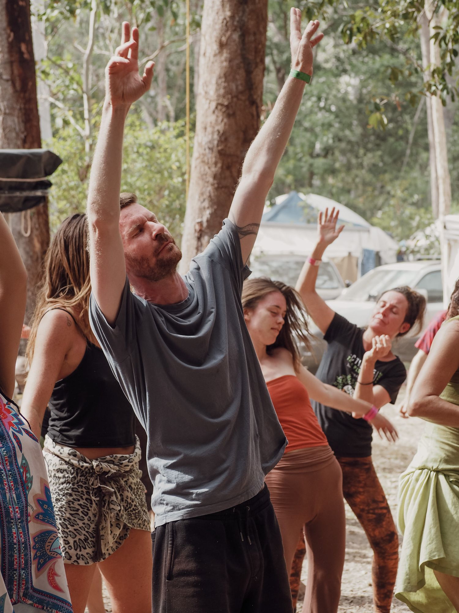 People raising their arms in celebration during an outdoor community wellness activity.