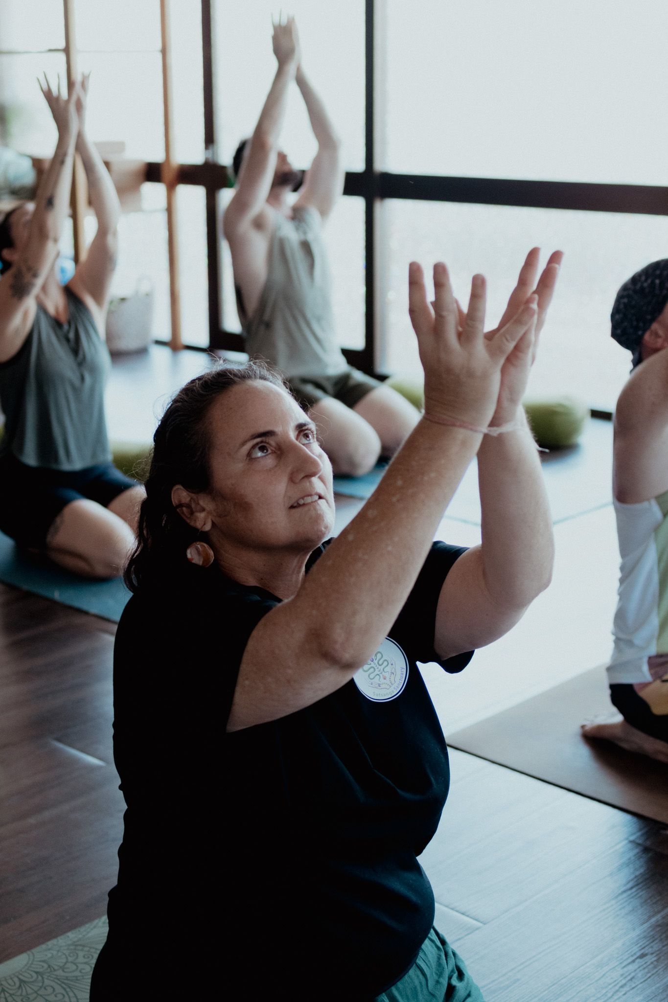 People reaching upward during a group fitness class in a bright studio space.