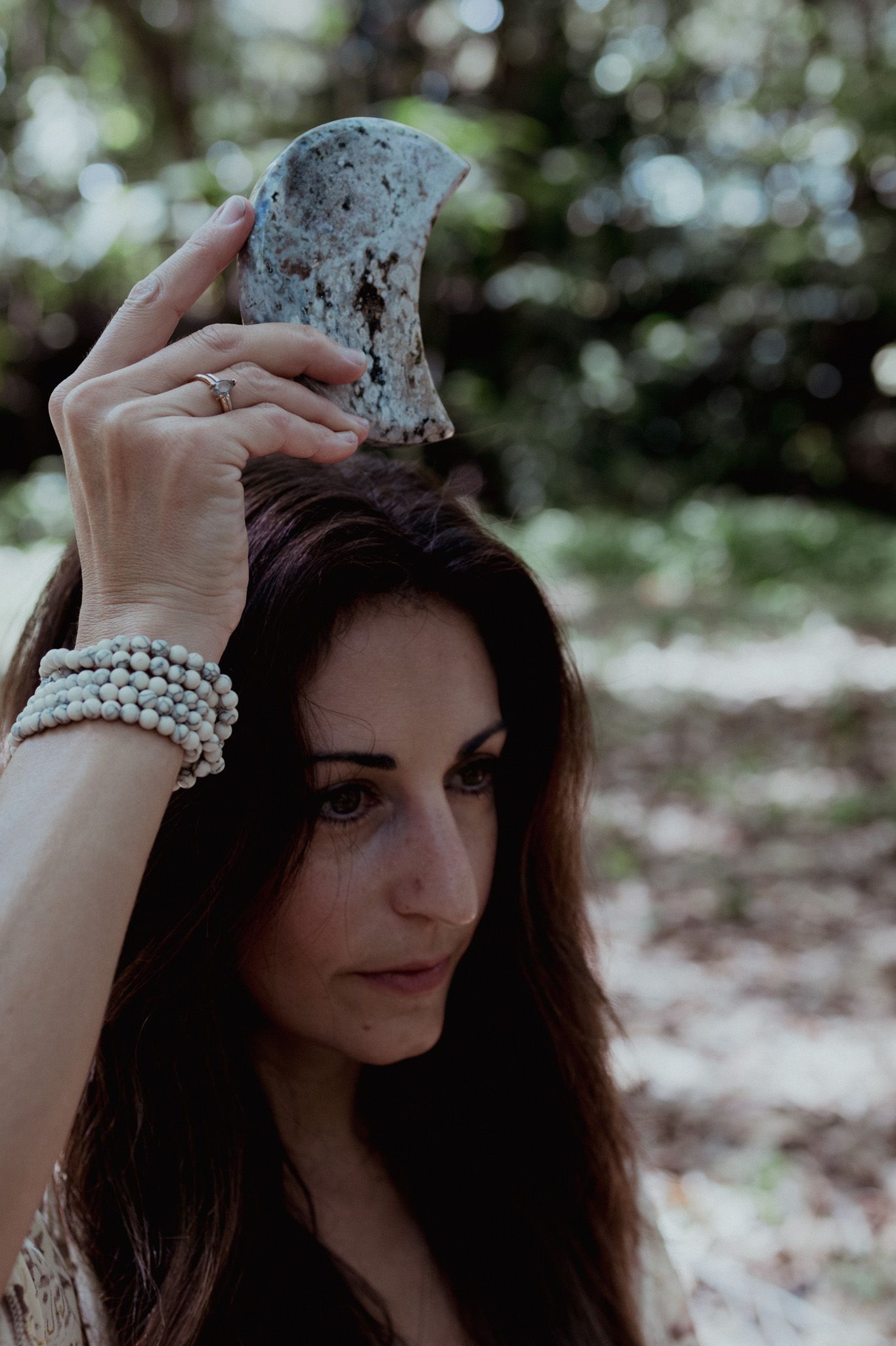 Pearl bracelets and lace details in a romantic forest portrait setting.