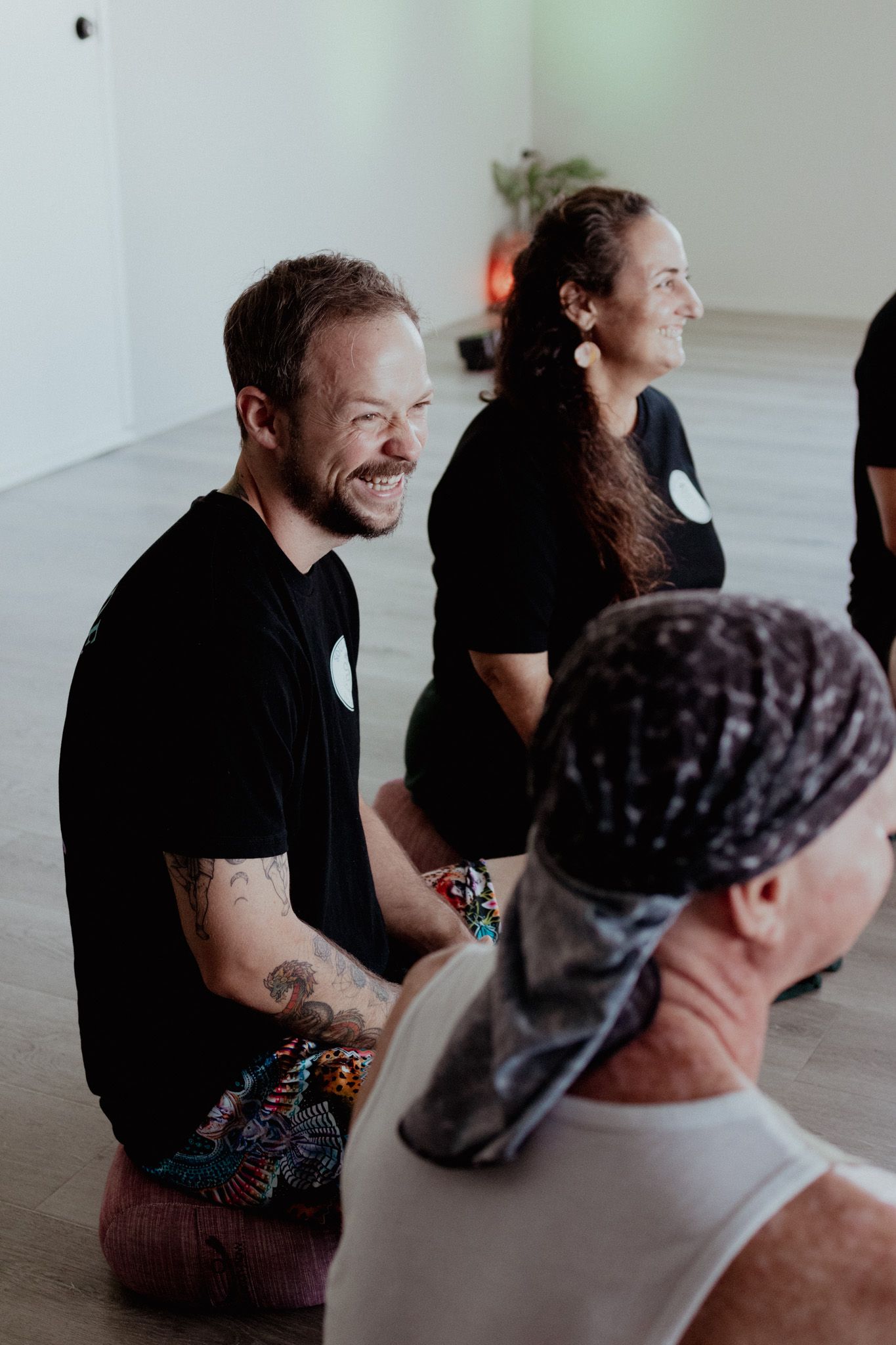 Group of people sitting on the floor engaged in casual conversation.