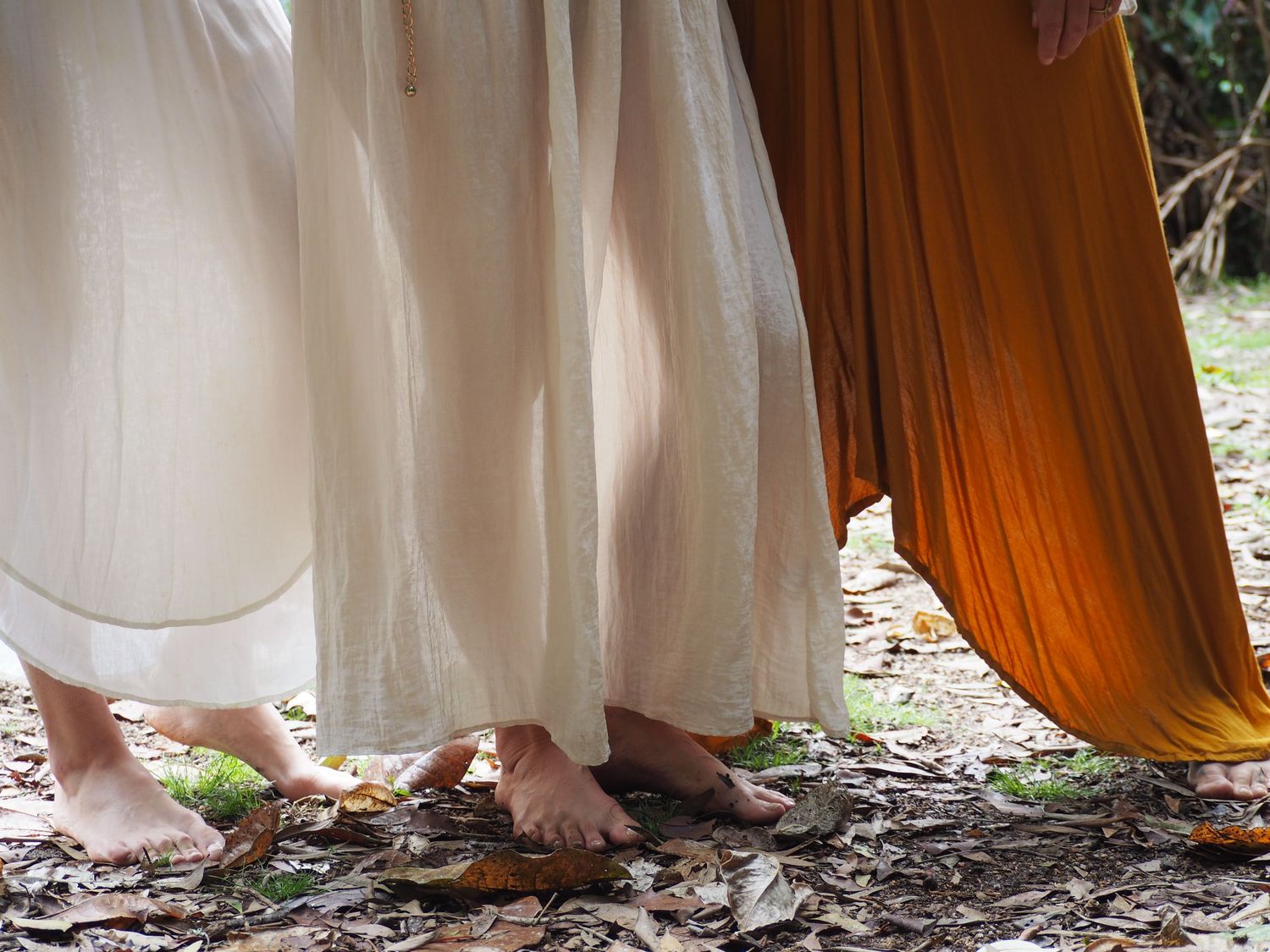 A group of people in flowing dresses stand together in a lush garden setting.