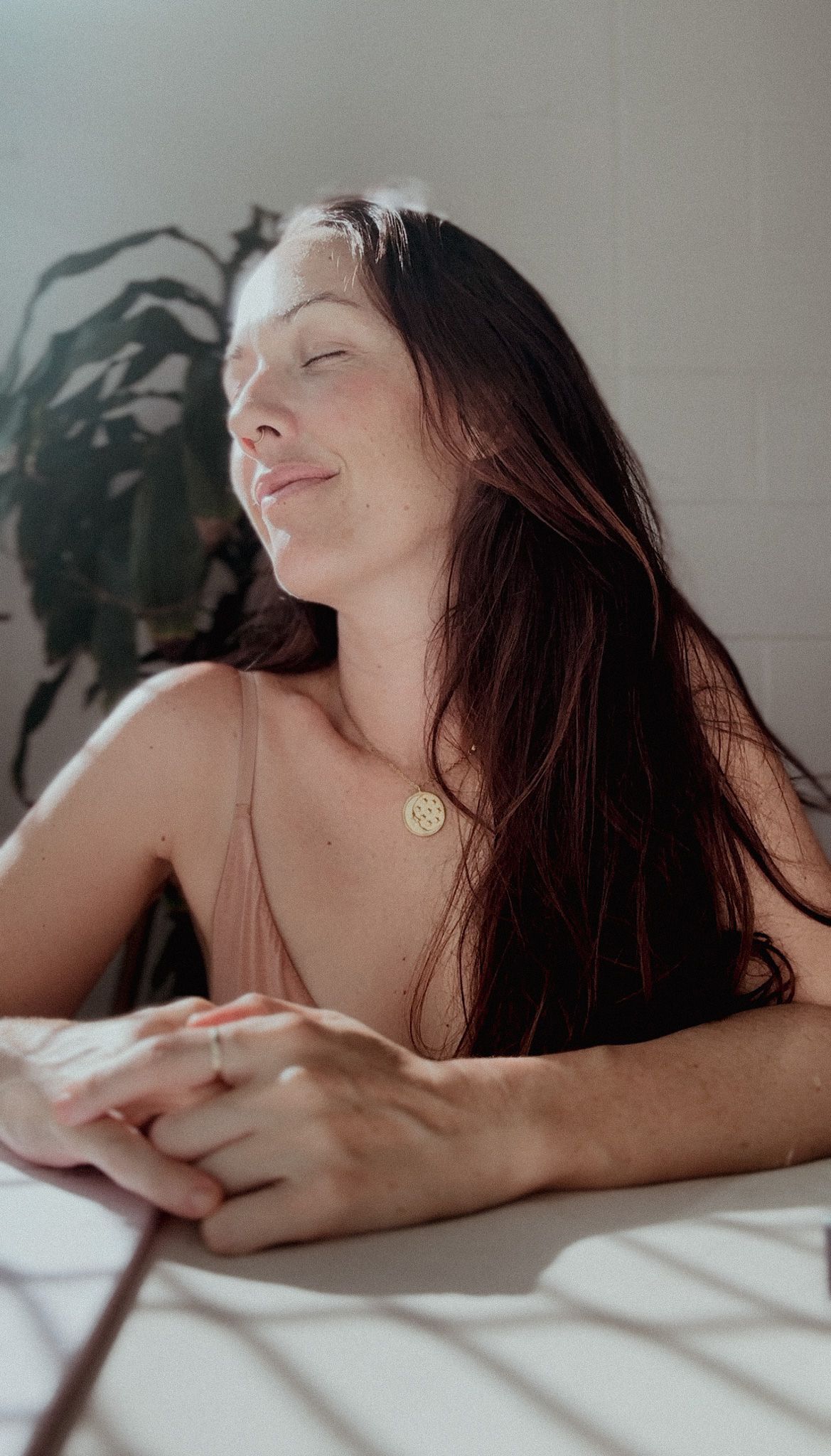 Woman with long dark hair resting peacefully in sunlit room.