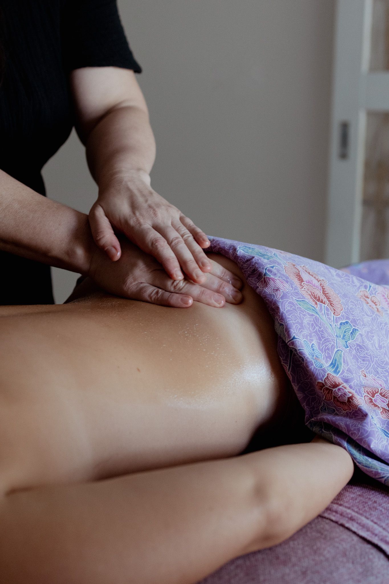 Therapeutic massage session focusing on leg muscles with decorative draping.
