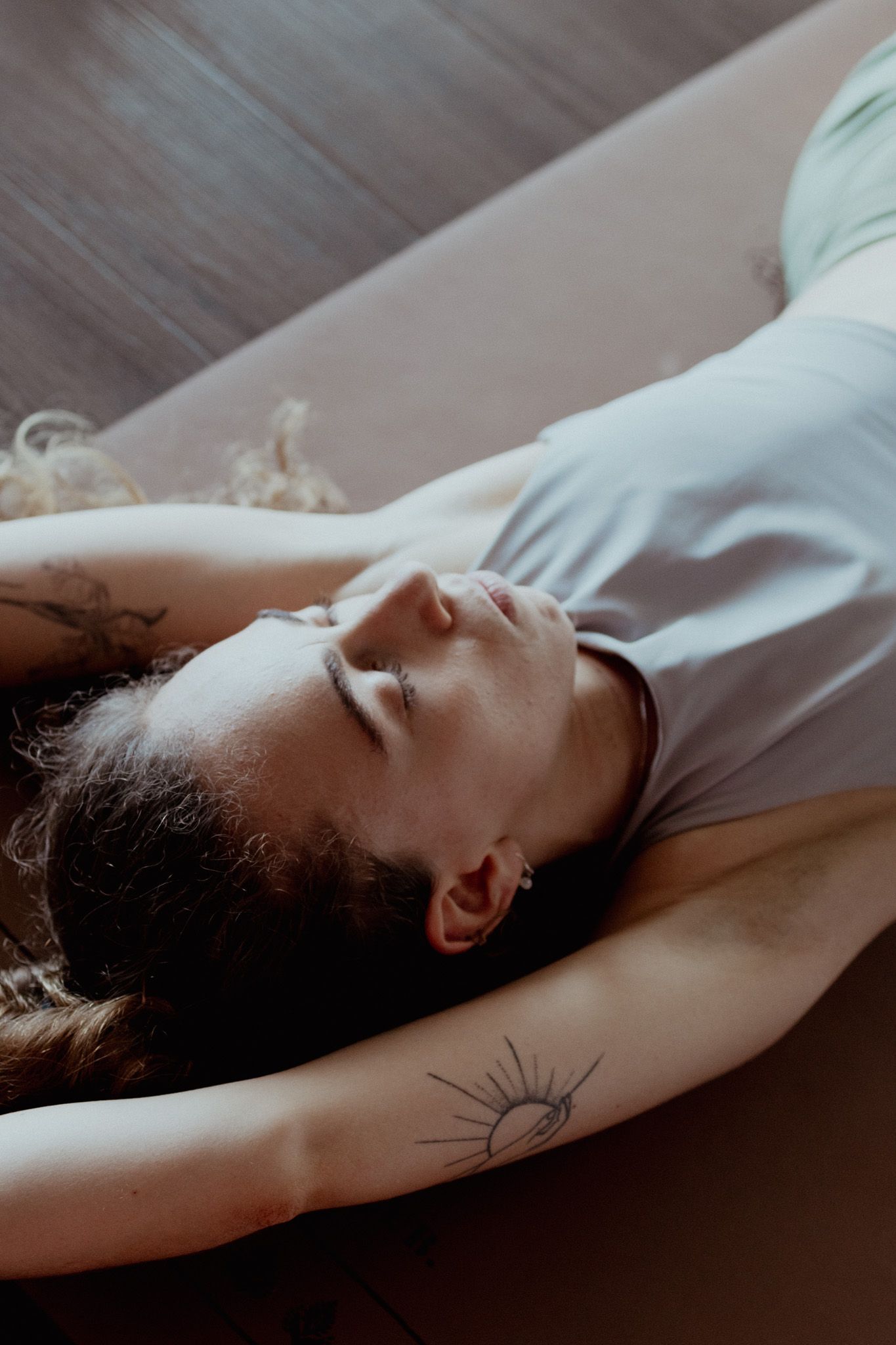 Person in relaxation pose on exercise mat with natural lighting.