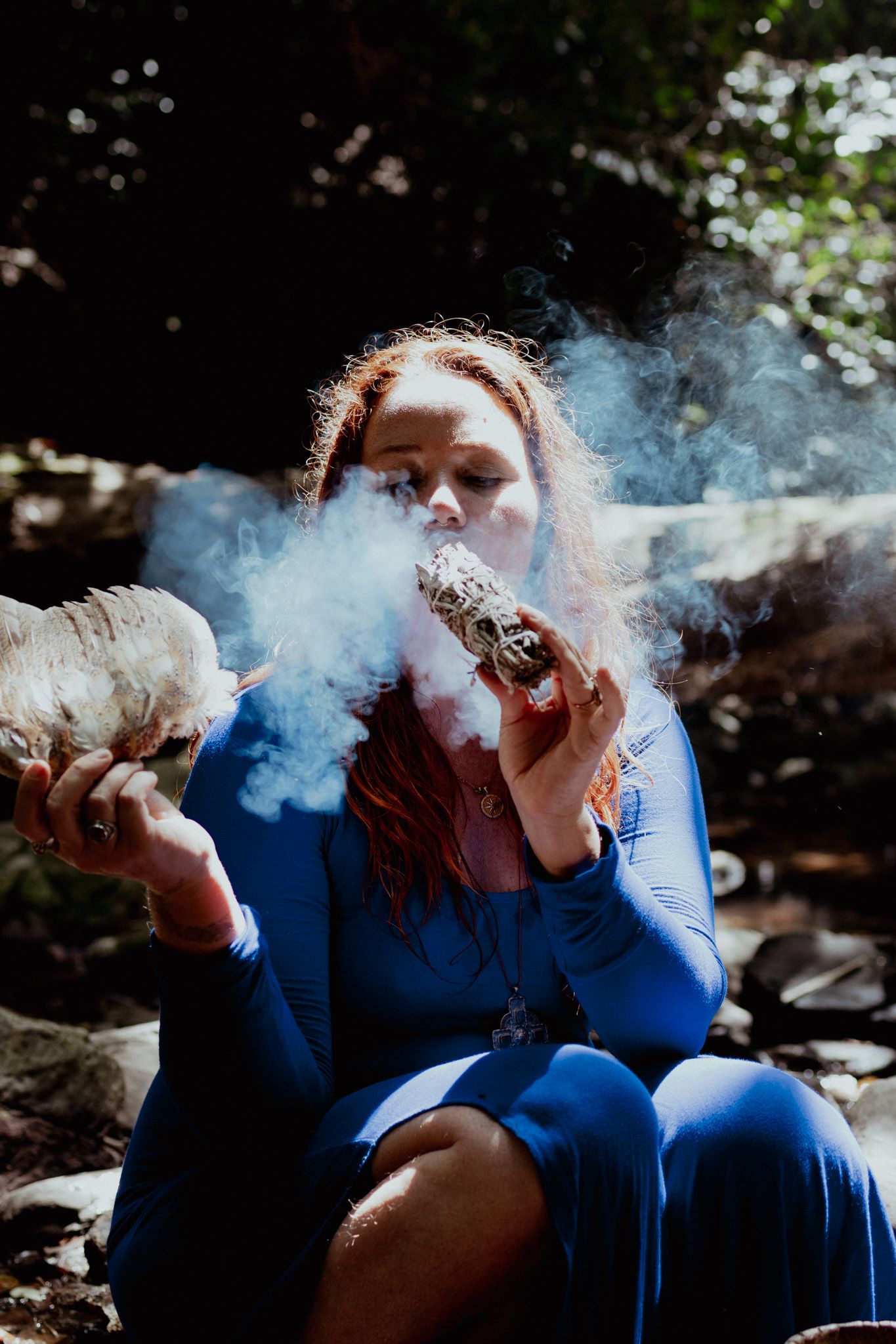 Blue smoke swirls create dreamy atmosphere in outdoor forest setting.