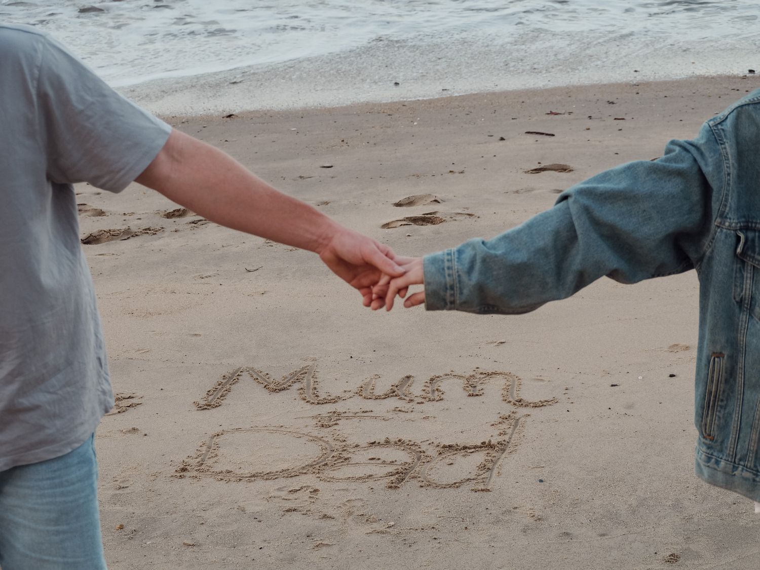 Writing messages in sand on a beach with footprints visible.
