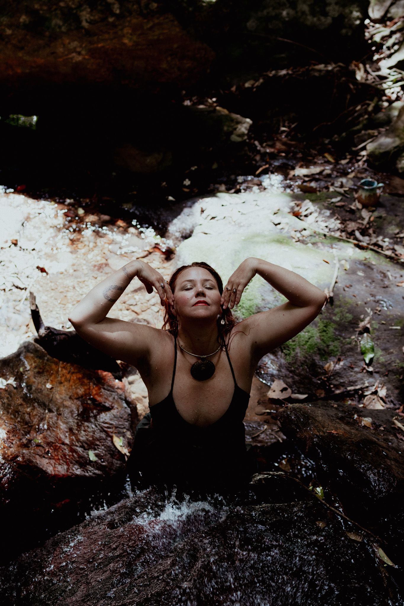 Artistic photo series showing reclining pose against dark rocky background.