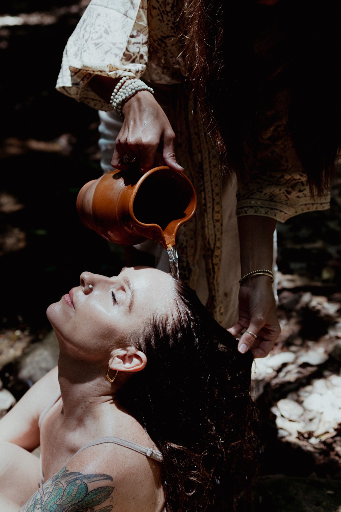 Moody portrait with water being poured in dramatic lighting outdoors.
