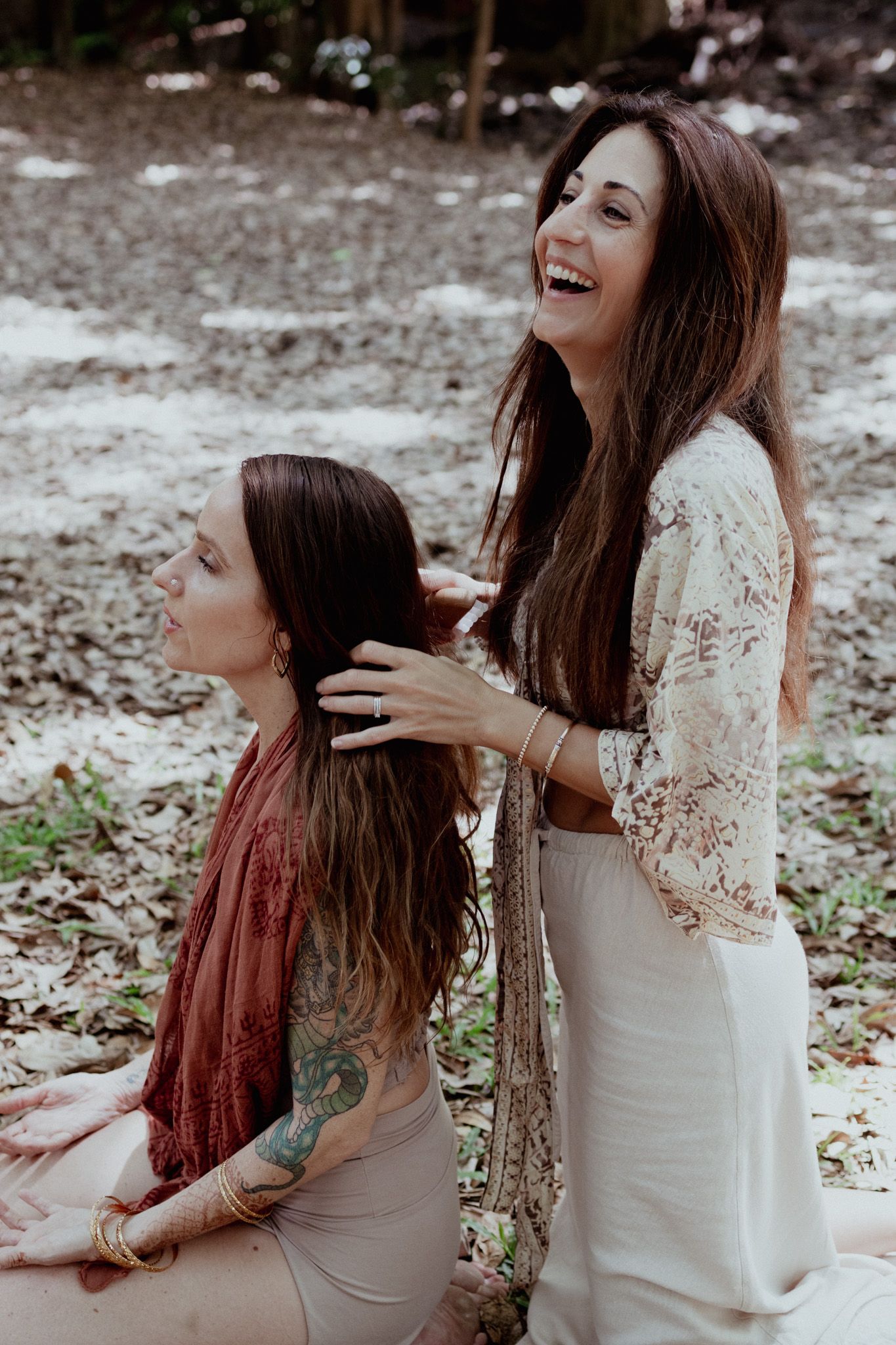Two people sharing joyful moments in a natural outdoor setting wearing contrasting dresses.
