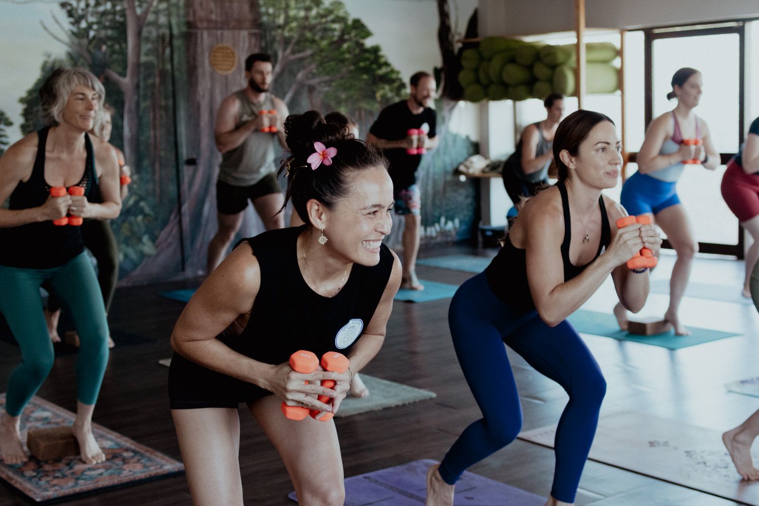 Group fitness class participants doing stretching exercises in an indoor studio.