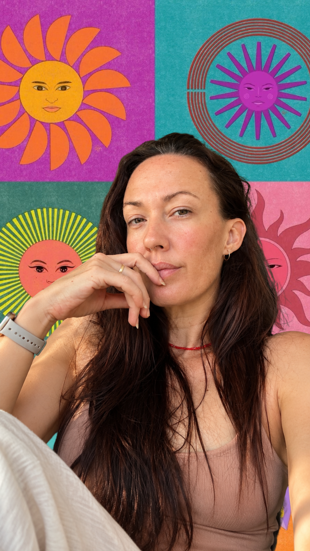 Woman with long dark hair poses thoughtfully against a vibrant colorful sun-themed backdrop wall art.