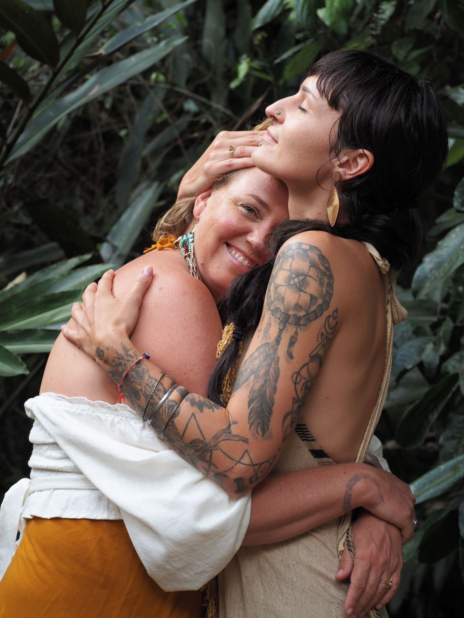 Two people embrace while wearing white and mustard colored clothing in an outdoor setting.