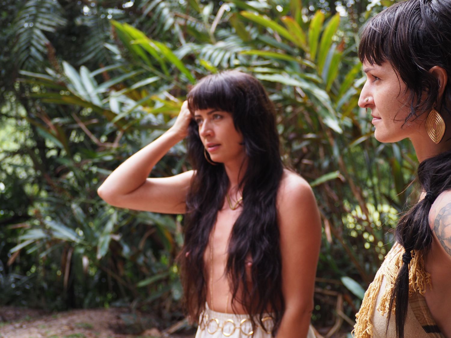 A person in a white dress poses in a tropical garden setting with lush greenery.