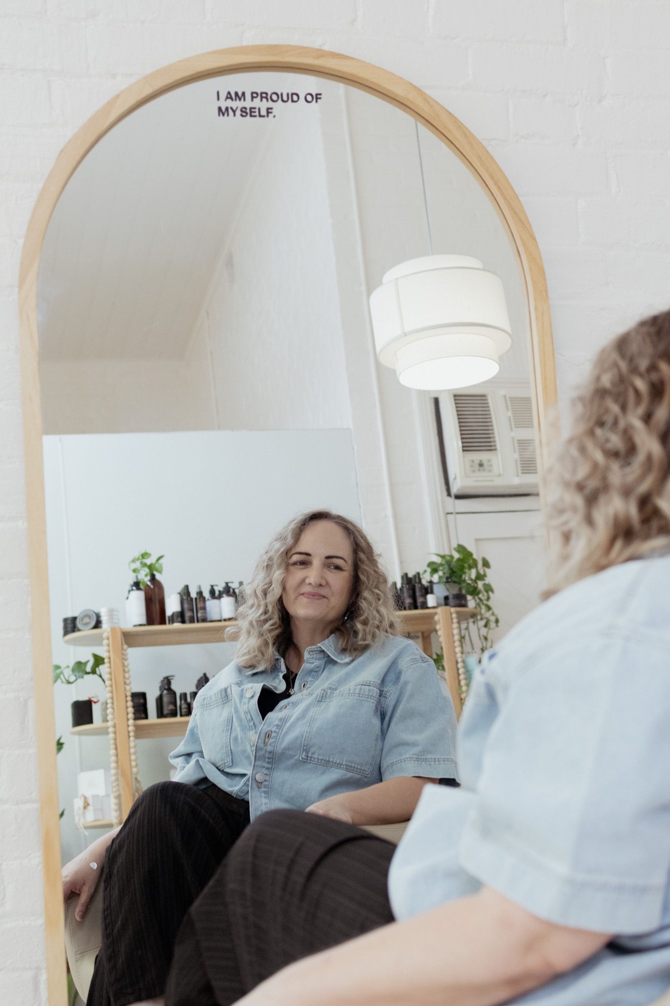 Interior shots of a modern salon space with arched mirror and minimal decor.