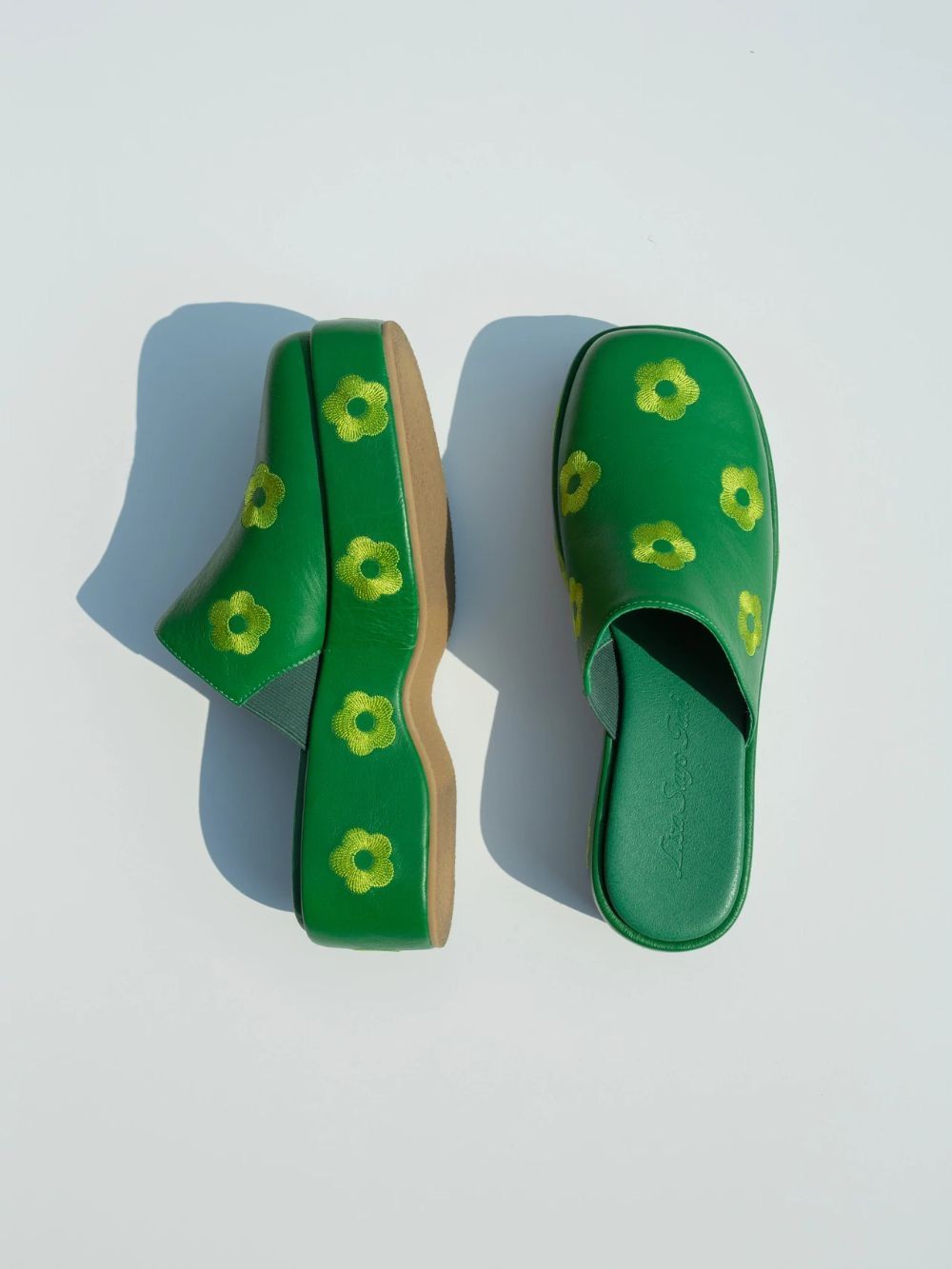 Green platform mule slides with yellow floral print pattern, shown as a pair on white background.