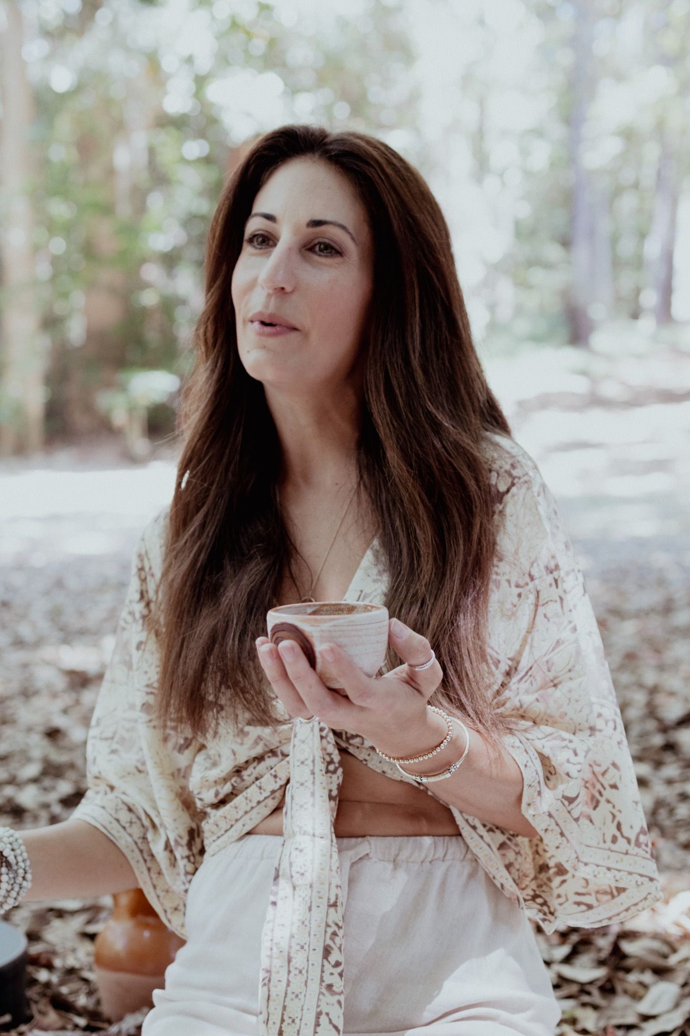 Lifestyle portrait in forest setting showing person in lace enjoying tea ceremony.