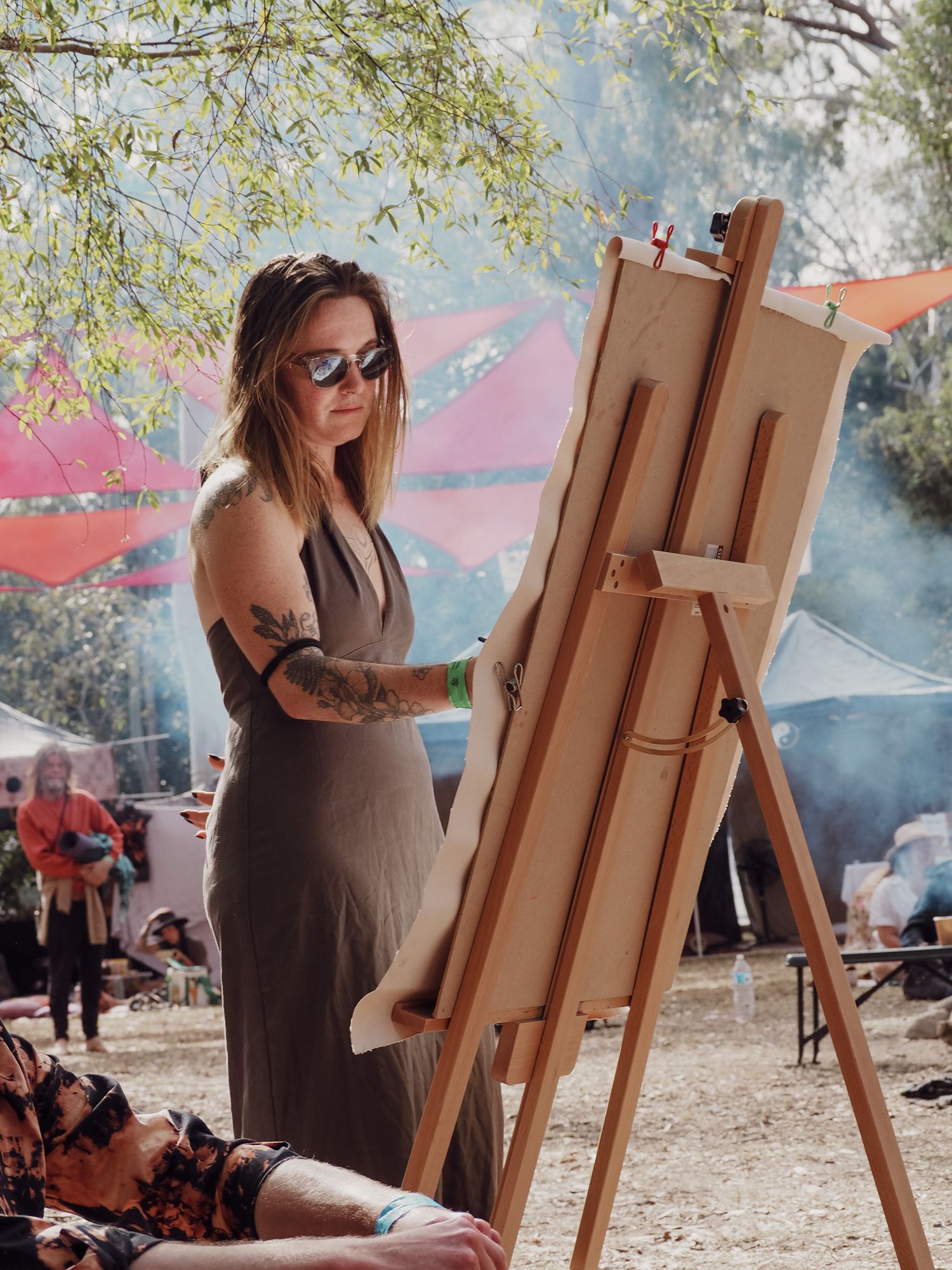 Artist working at wooden easel during outdoor festival with smoky atmosphere.