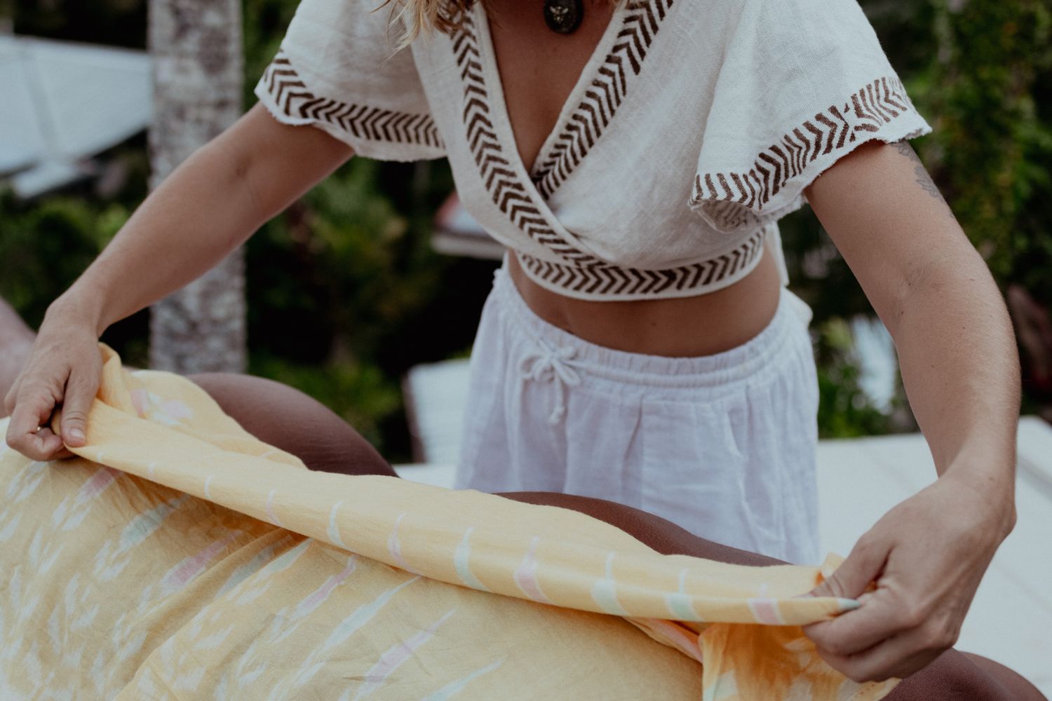 Hands preparing massage supplies outdoors in natural setting.