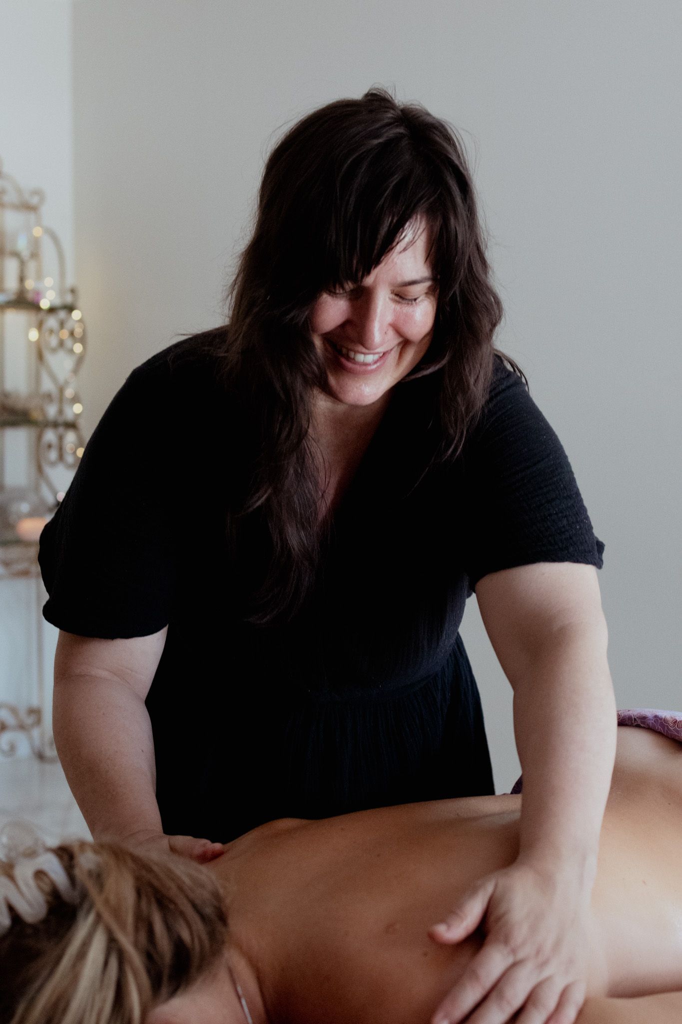 Massage therapist in black attire providing professional bodywork treatment.