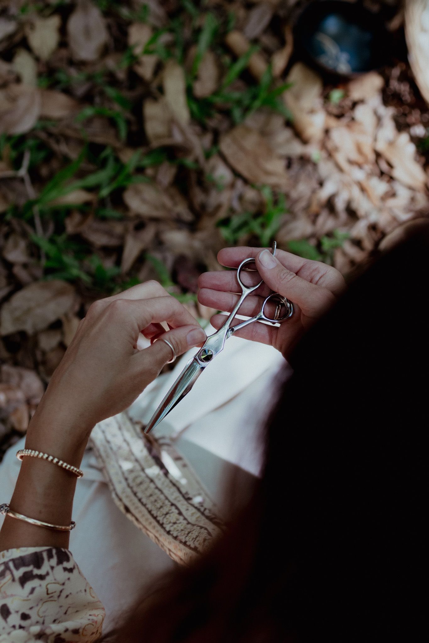 Close-up of hands holding delicate scissors against white lace fabric.
