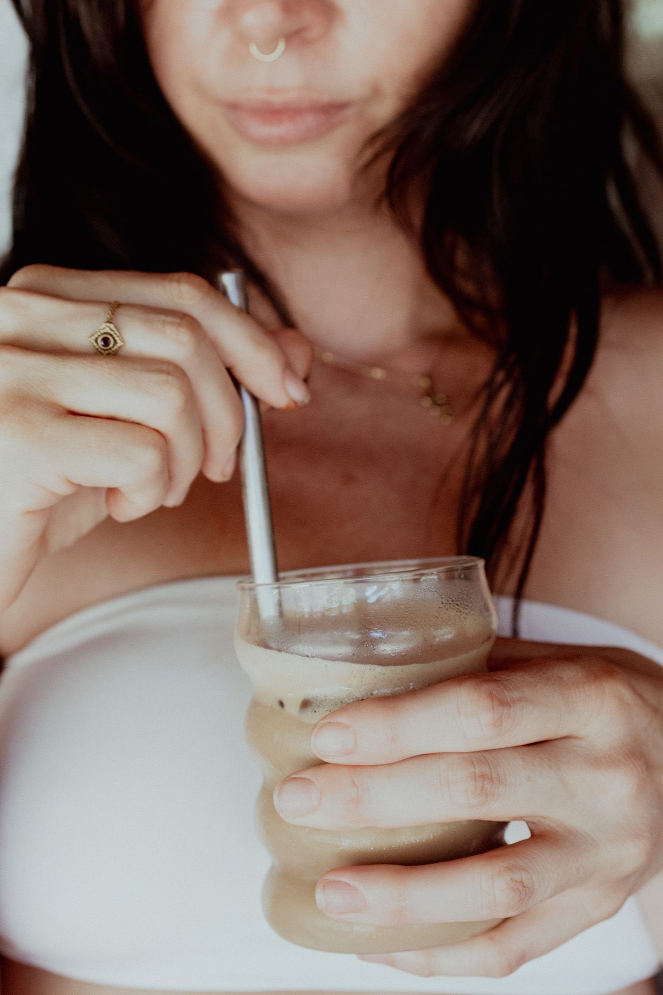 Close-up view of hands holding a glass of creamy beverage.