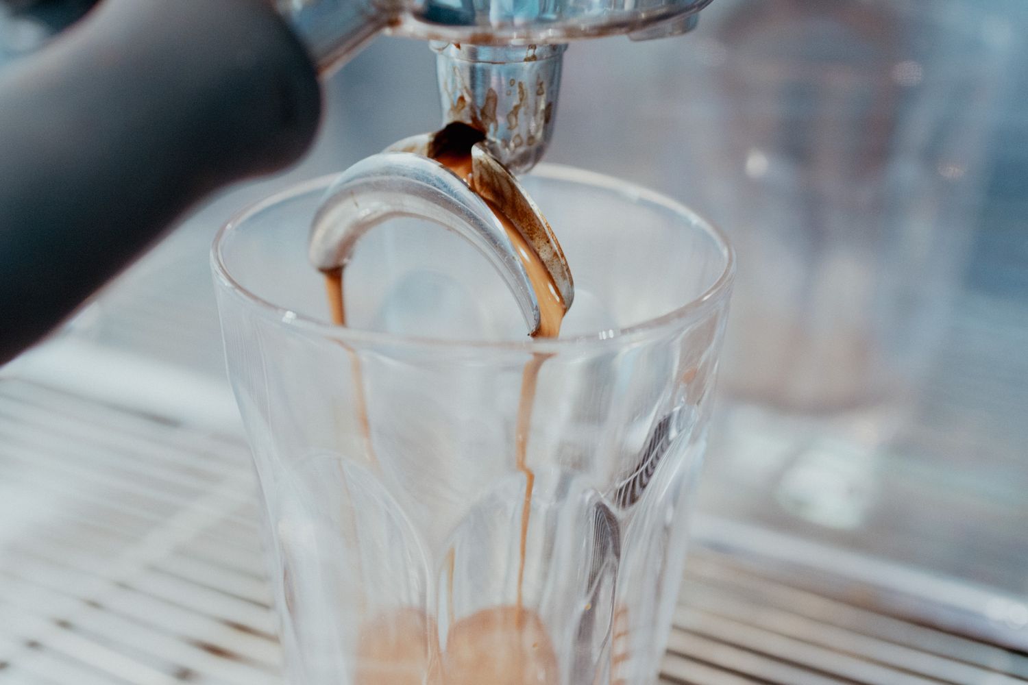 Coffee being poured into a clear glass cup creating a beautiful cascade effect.