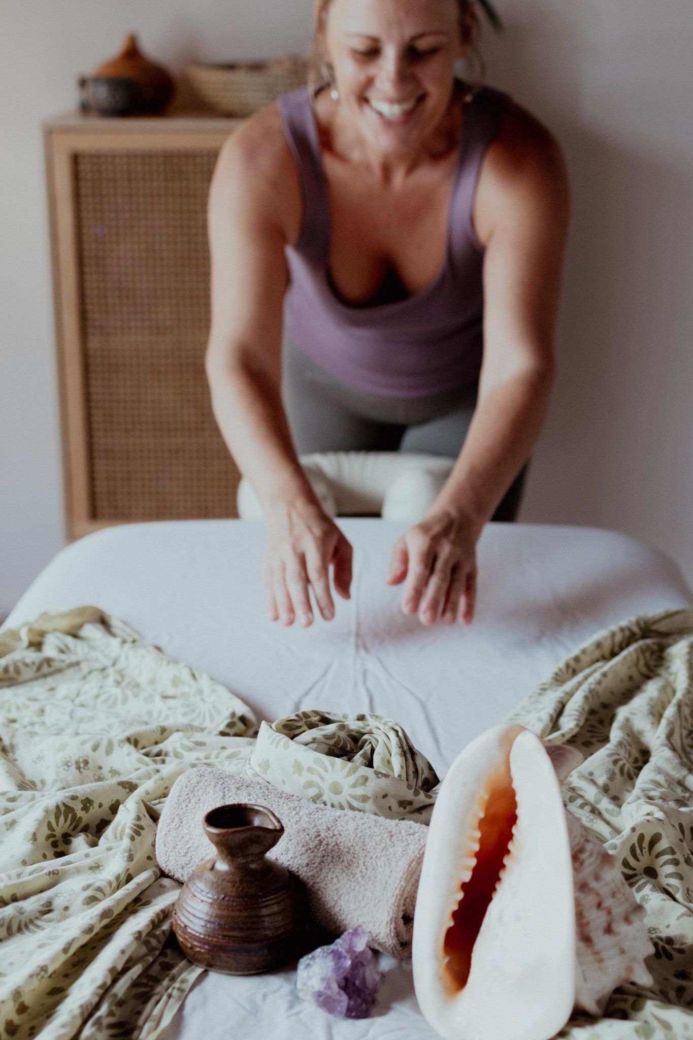 Various healing crystals and stones arranged on textured fabric with hands reaching to arrange them.