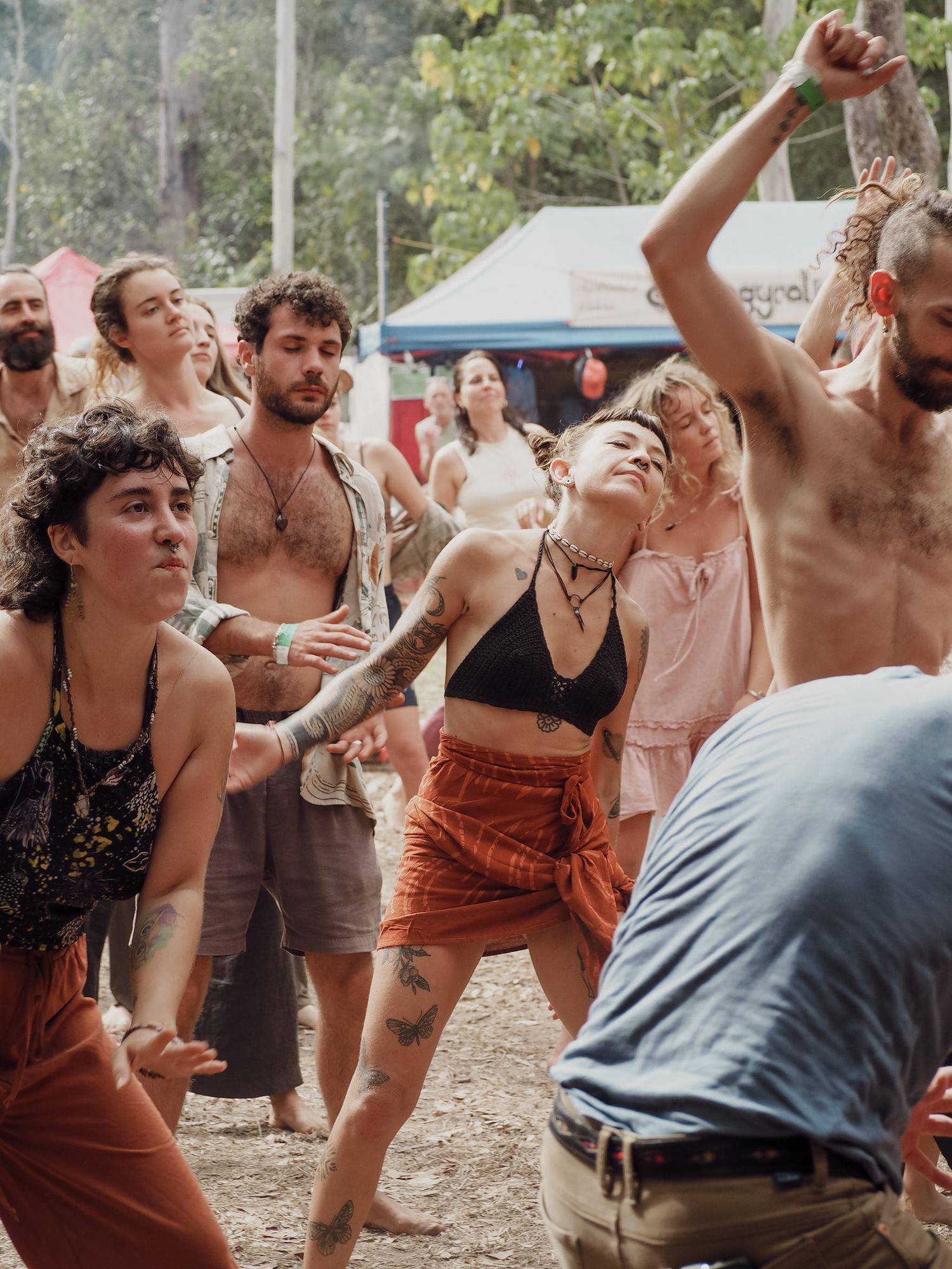 Group of festival-goers dancing energetically outdoors in casual summer attire at a daytime event.