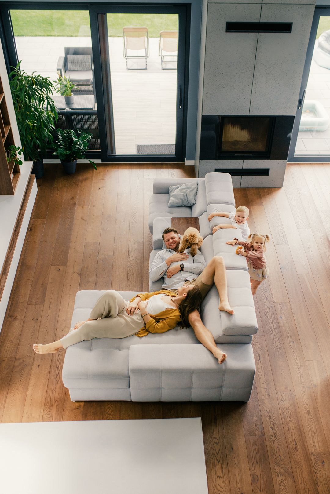 Top view of a family of four lounging on a white sectional sofa in a spacious modern living room.