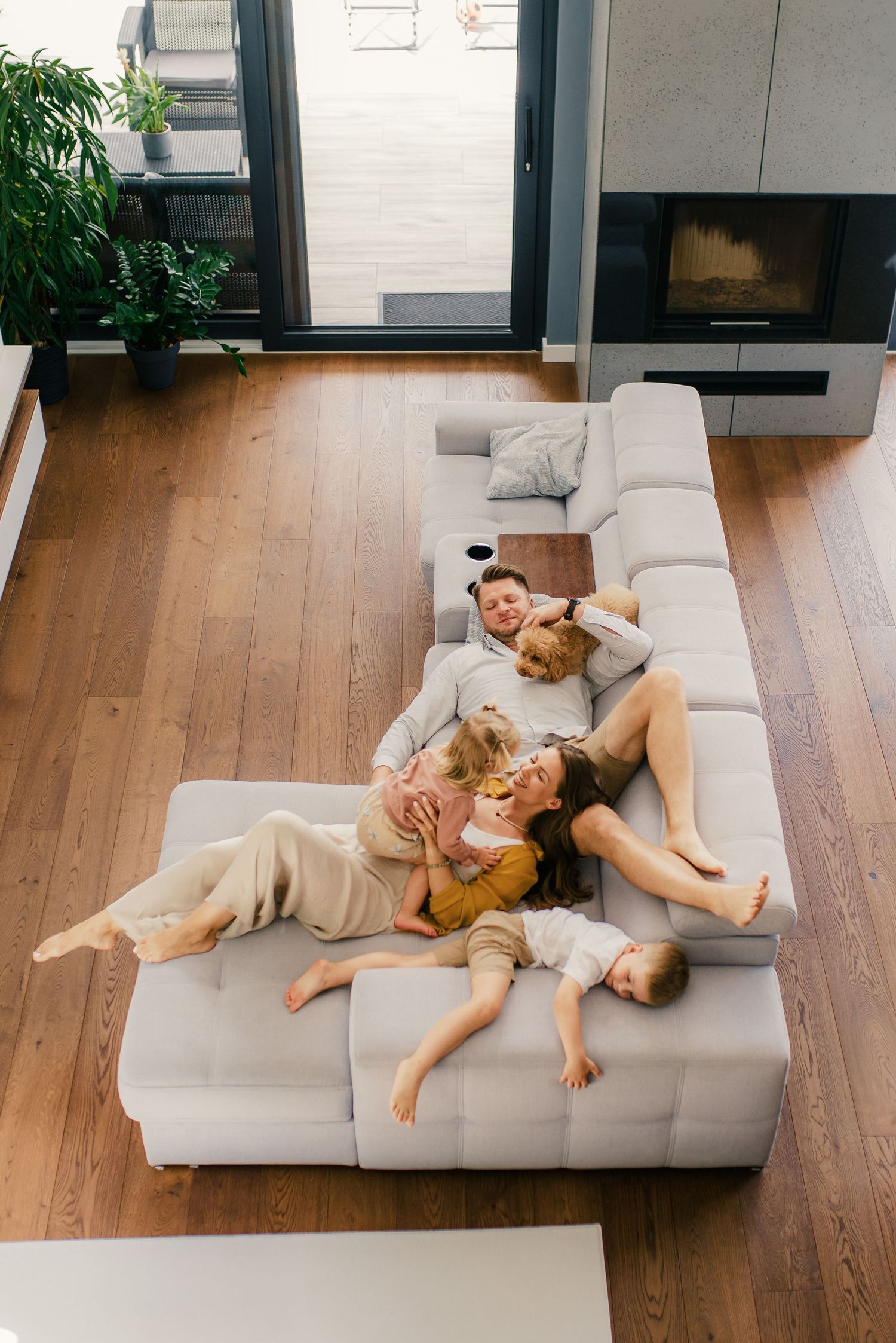 Family of four relaxing together on a large gray sofa viewed from above.